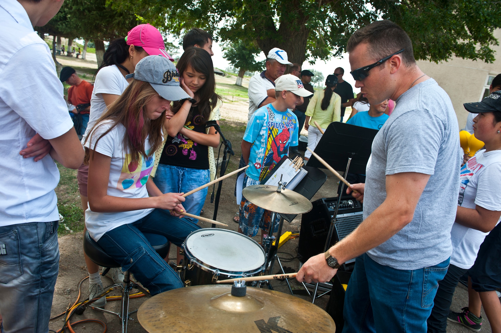 Senior Airman Simon Thomsen gives tips on how to play the drums after the U.S. Air Forces Central Band "Vector" performance at the Mayak Camp, Kyrgyzstan, July 23, 2012. Vector played for various audiences on a four-day tour throughout the Issyk-Kul province. Thomsen is a drummer deployed out of the Channel Islands Air National Guard Station, Calif. and is a native of Los Angeles. (U.S. Air Force photo/Senior Airman Brett Clashman)