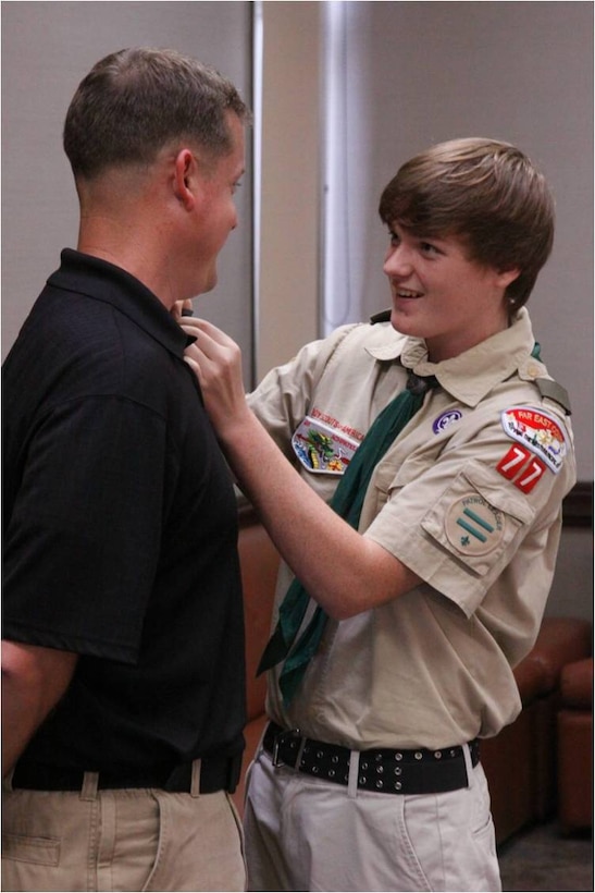 Eric D. Cox, Boy Scouts Troop 77 Star Scout, pins Mike D. Cox, his father, with a traditional pin for Eric’s accomplishments during a Court of Honor ceremony at Yujo Hall here July 31, 2012. Many of the Scouts’ parents attended the ceremonies. Founded Feb. 8, 1910, the Boy Scouts of America adopted a mission instilling ethical and moral values in all its members.