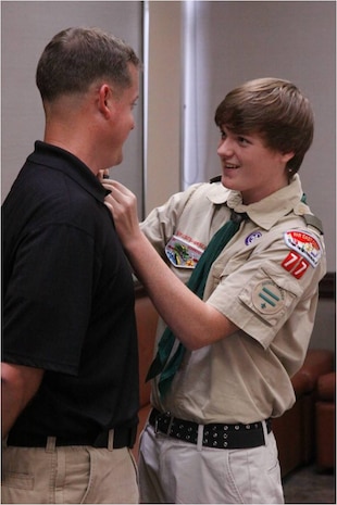 Eric D. Cox, Boy Scouts Troop 77 Star Scout, pins Mike D. Cox, his father, with a traditional pin for Eric’s accomplishments during a Court of Honor ceremony at Yujo Hall here July 31, 2012. Many of the Scouts’ parents attended the ceremonies. Founded Feb. 8, 1910, the Boy Scouts of America adopted a mission instilling ethical and moral values in all its members.