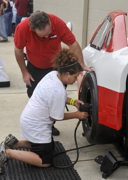 Madison Francis attempts to change a tire as Earl Hayes provides help at the NASCAR Social June 1, 2012, at Dover Air Force Base, Del. (U.S. Air Force photo by Tech. Sgt. Chuck Walker)