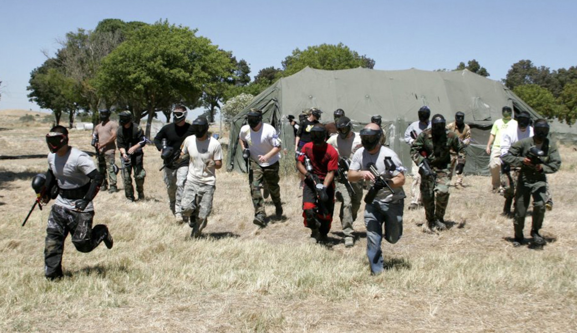 Travis Airmen and civilians charge from a tent during a game of paintball on Aug. 26, 2011, during Wingman Day festivities. (Courtesy photo)