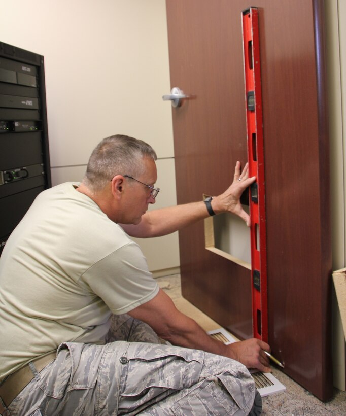 Tech. Sgt. Dan Rubliatus uses a level to make sure his work is correct before attaching the metal air vent.  Rubliatus and several other 932nd Civil Engineers worked in building 3650 hanging wallpaper, moving audio-visual wiring and other tasks while on annual tour.  The home station project enabled CES members to utilize a full range of carpentry skills.  (U.S. Air Force photo/Tech. Sgt. Dan Oliver
