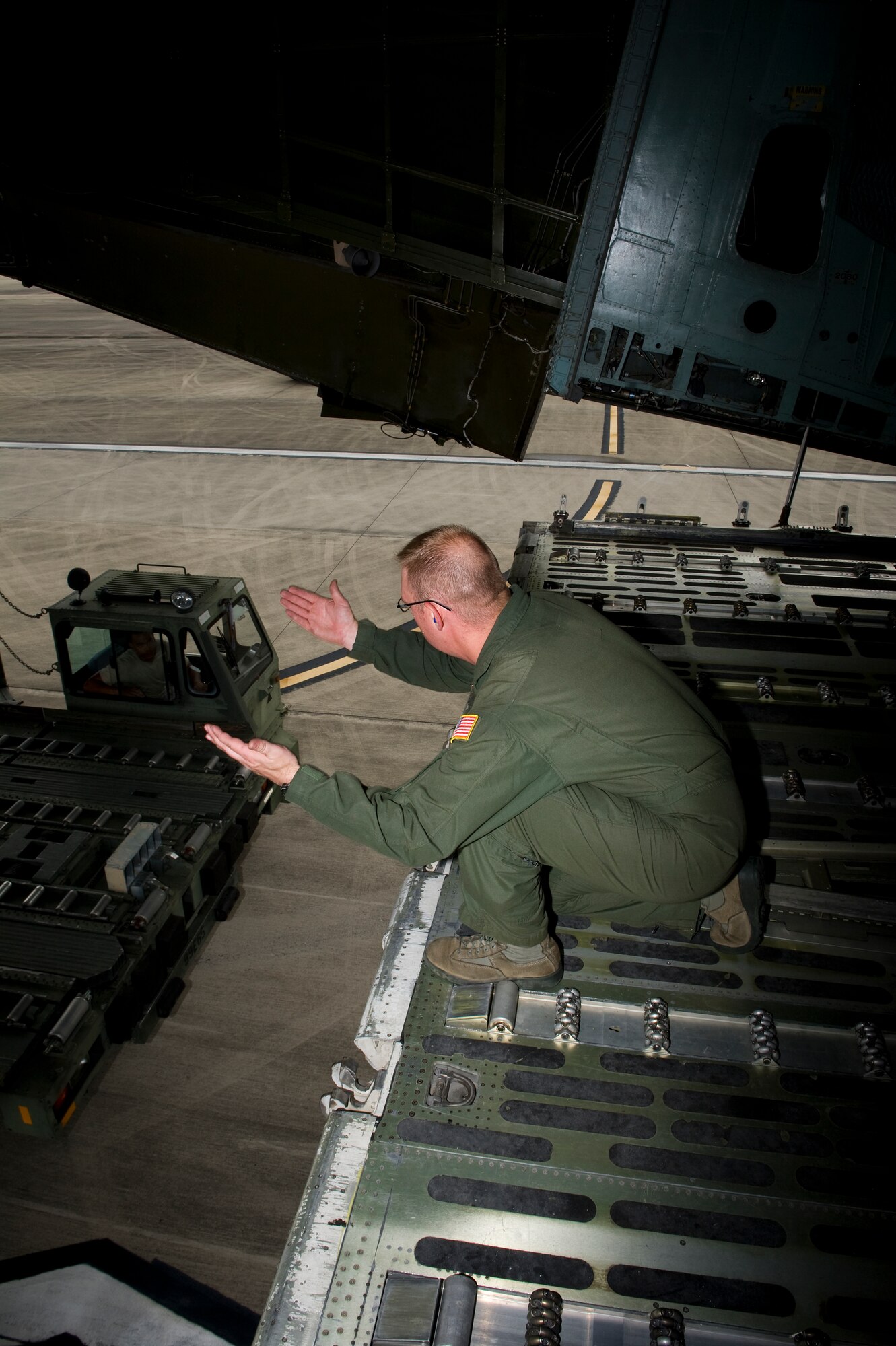 U.S. Air Force photo Staff Sgt. Erik Richard, a loadmaster with the 337th Airlift Squadron out of Dover Air Force Base, Del., signals that a vehicle can push back after unloading on the flightline at Hurlburt Field, Fla., June 1st, 2012. The equipment being loaded was bound for Hawaii to set up a U.S. Navy school house. (U.S. Air Force photo/Airman 1st Class Christopher Williams)(Released)