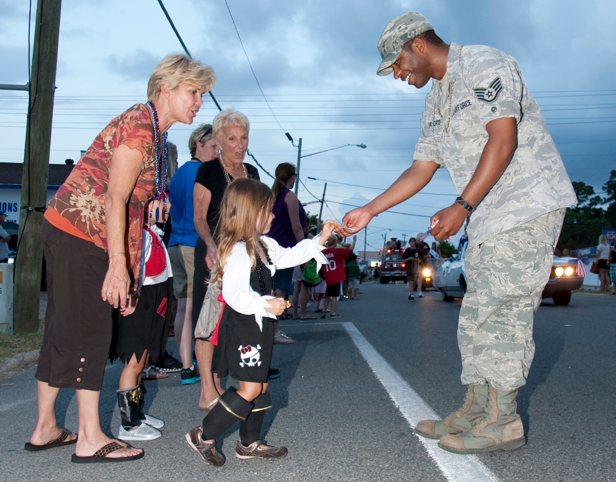 U.S. Air Force Staff Sgt. Thomas Rutherford, a financial technician of 1st Special Operations Comptroller Squadron, hands candy to a child while at the 57th Annual Billy Bowlegs Torchlight Parade at Fort Walton Beach, Fla., May 31, 2012. Thousands of people lined the parade route to receive candy and beads from floats. (U.S. Air Force photo / Airman 1st Class Benjamin Kim)(RELEASED)