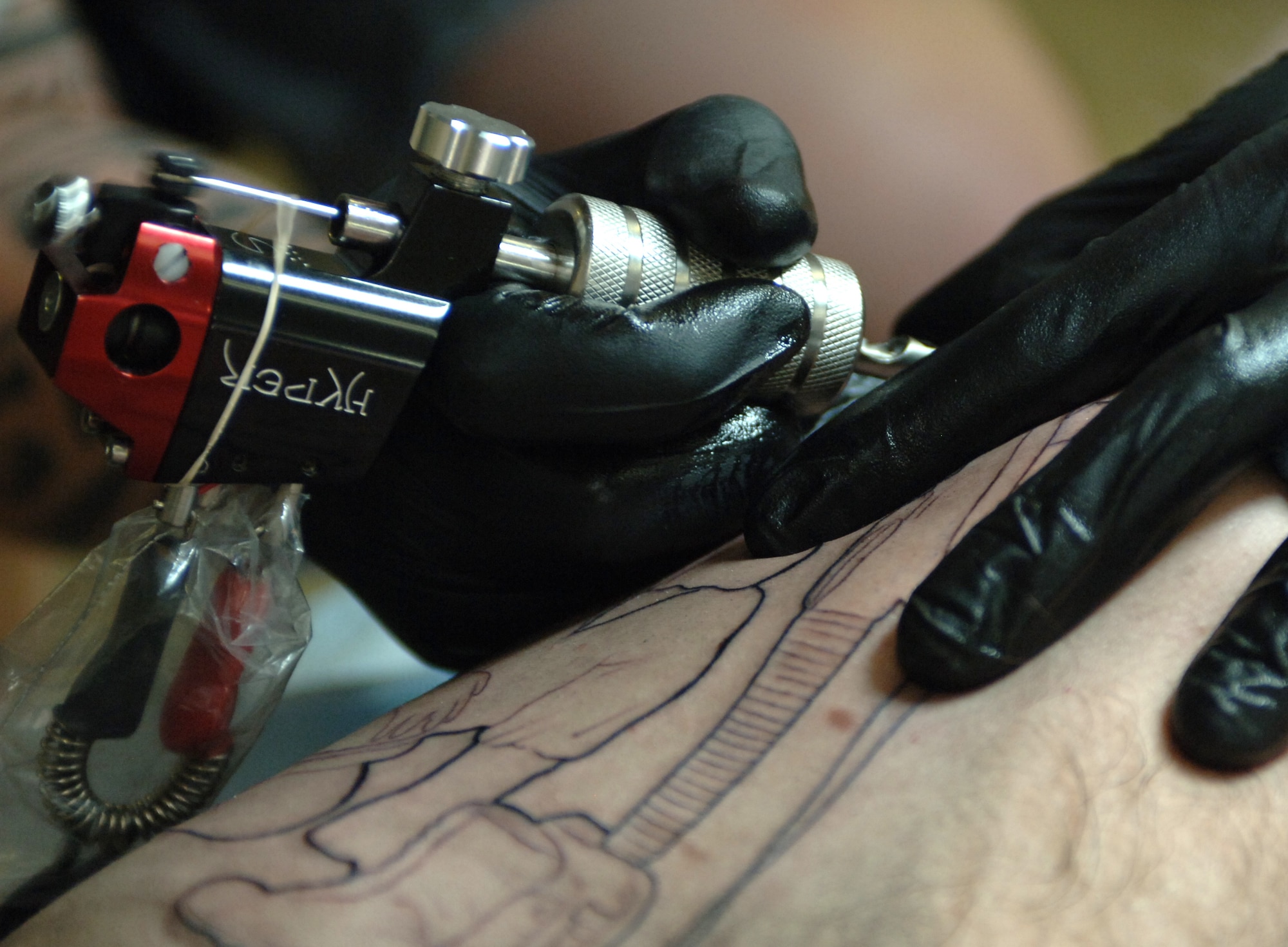 While tattooing a regular client former U.S. Air Force Staff Sgt. Matthew Pehrson, owner and operator of a local tattoo parlor, carefully maneuvers a needle across his flesh canvass, May 30, 2012, at Mountain Home, Idaho. From the spiritual significance of the markings for indigenous tribesmen to their showmanship in the American circus, tattoos have always found their way into an array of cultures – including that of the military. (U.S. Air Force photo/Airman 1st Class Shane M. Phipps)