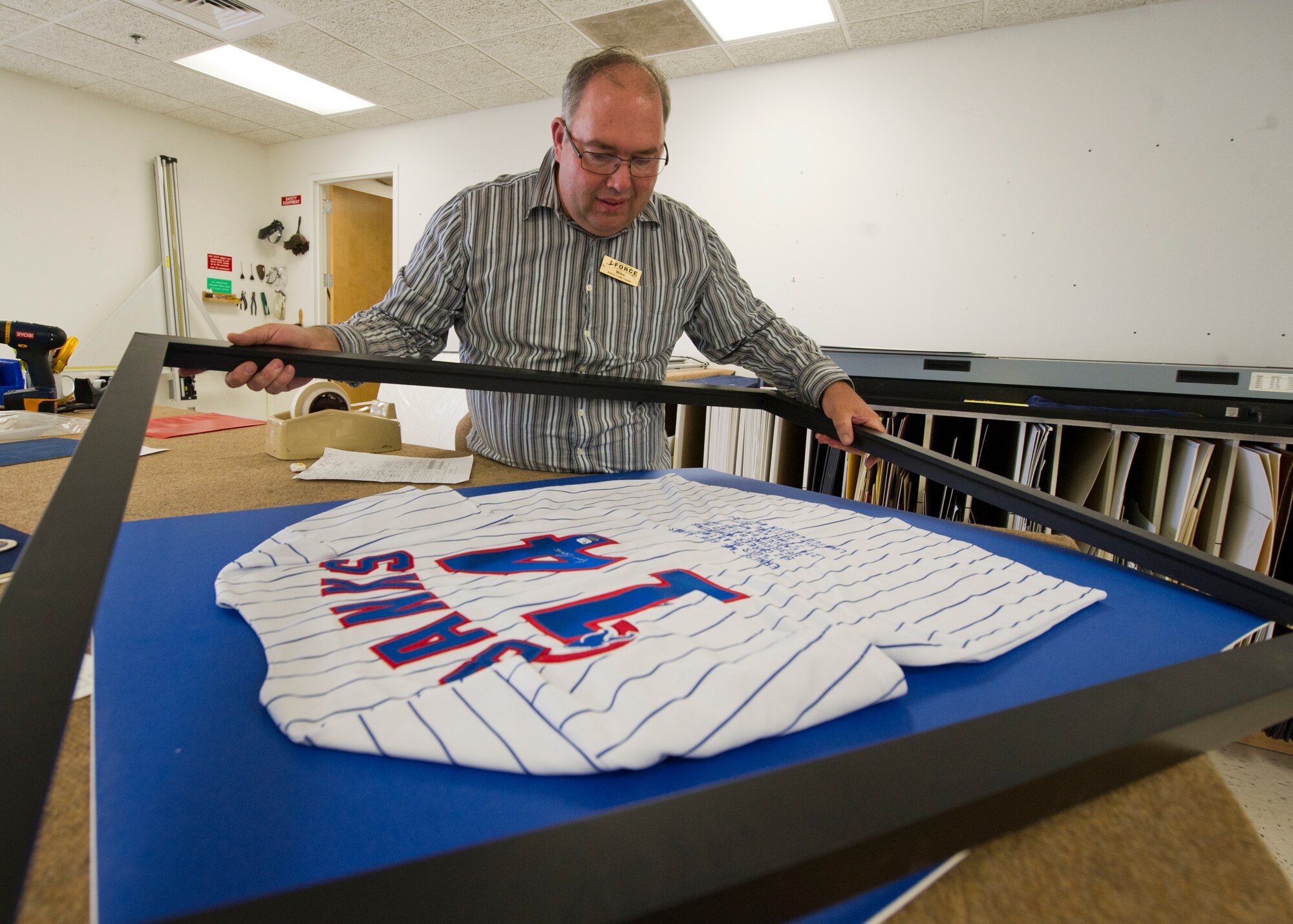 HOLLOMAN AIR FORCE BASE, N.M. – Mike Smith, a framing specialist at the Arts and Crafts Center, frames an autographed jersey May 29. Smith also frames shadow boxes, flags, coins and uniforms for about half the cost of going to a frame shop outside of the base. Besides framing, the Arts and Craft Center also features an engraving, embroidery and ceramics shop open to all members of Team Holloman. (U.S. Air Force photo by Airman 1st Class Siuta B. Ika/Released)