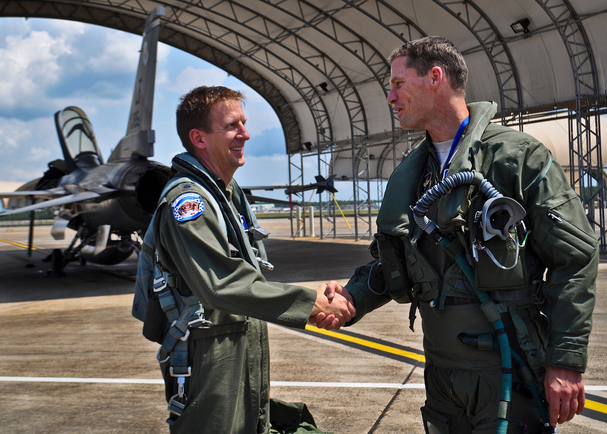 Lt. Col. Eric Smith (left) congratulates Lt. Col. Lee Kloos on becoming the latest qualified joint strike fighter pilot and DOD’s first non-developmental test pilot to qualify, May 31 at Eglin Air Force Base, Fla. After completing his flight, is now a qualified instructor pilot for the F-35 Lightning II.  Smith, the director of operations with the 58th FS and the first Air Force qualified pilot, served as Kloos' flight evaluator.  (U.S. Air Force photo/Maj. Karen Roganov)
