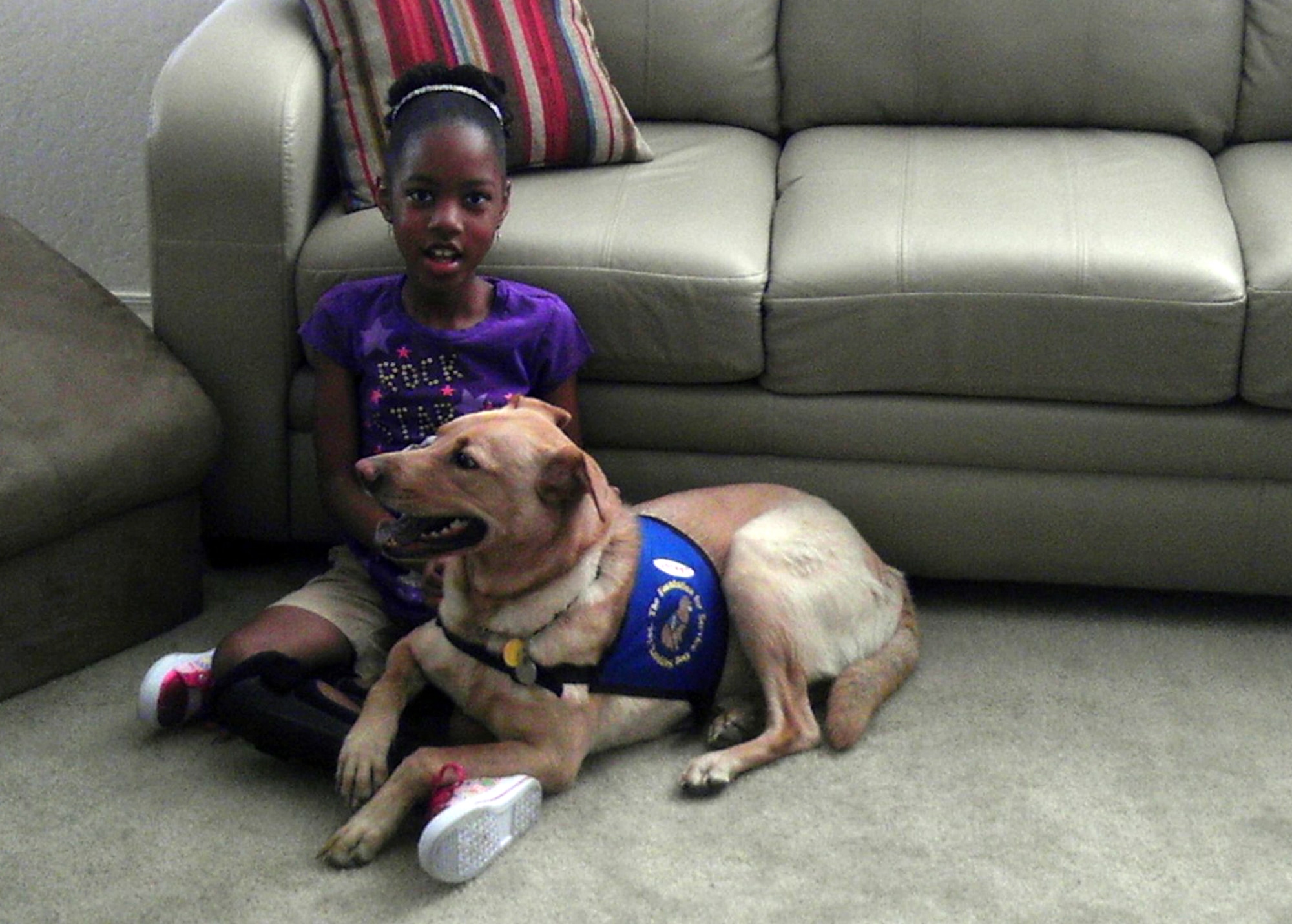 Jonna Dukes, daughter of Tech. Sgt. Zenobia Muhammad, 56th Maintenance Operations Squadron scheduler, sits with her service dog, Bailey. Jonna received her service dog with the help of the Exceptional Family Member Program, designed to help those in the armed forces who have family members with special needs. For more information on the EFMP, call the Airman & Family Readiness Center at (623) 856-6550.  (Courtesy photo)