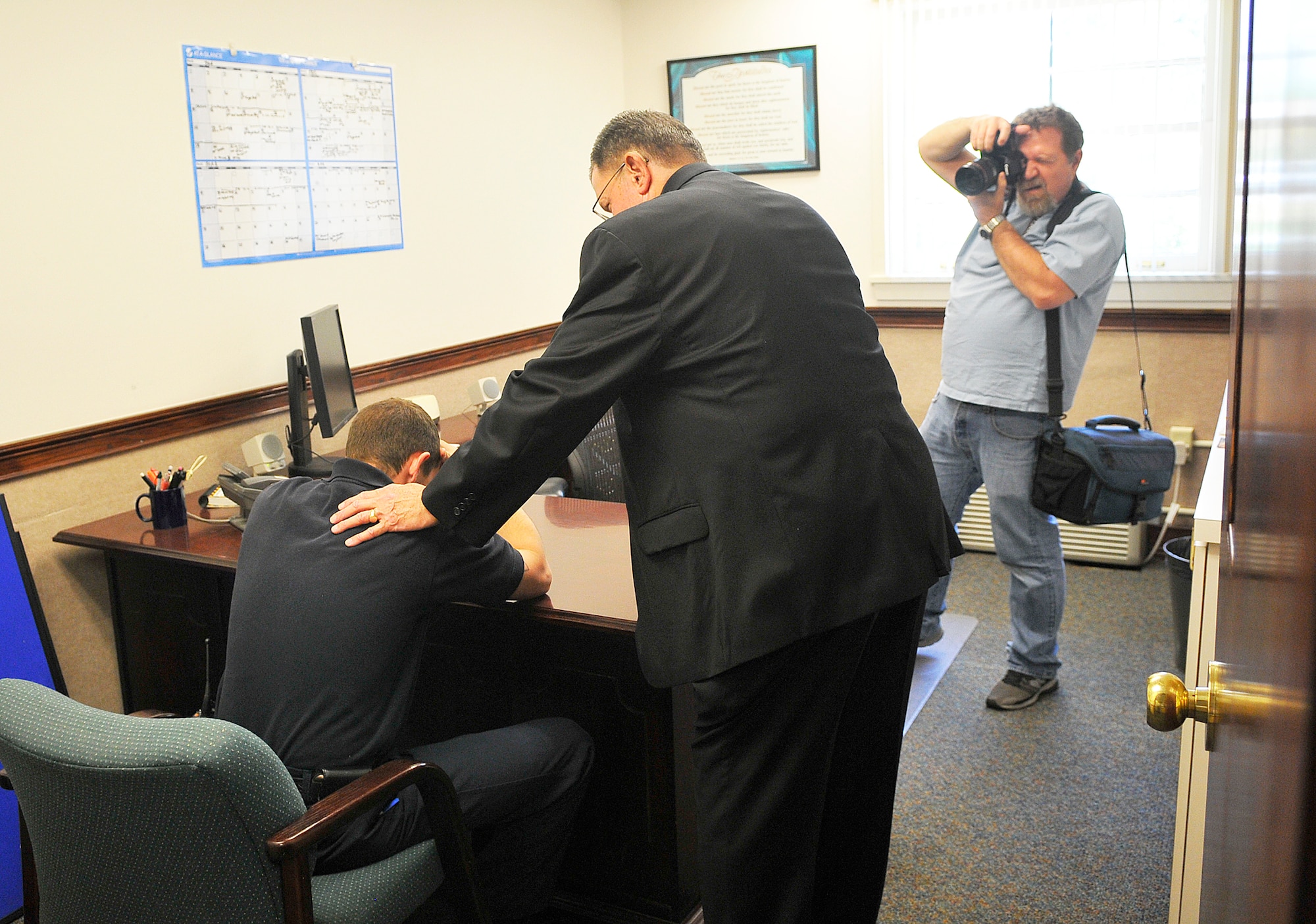 Bob O'Donnell, still photographer,shoots a photo at Robins Chapel of Catholic Chaplain Thomas Fey consoling a distraught firefighter. A crew was at Robins May 21-23 to shoot photos and film segments for an Air Force Health and Safety Officer course. (U. S. Air Force photo by Sue Sapp)