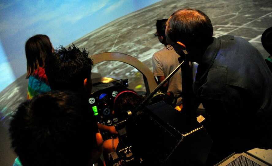 A simulator instructor shows students from the Laughlin Education Enrichment Program how to fly the T-6A Texan II at Jarvis Hall during a tour of Laughlin Air Force Base, Texas, May 30, 2012. The LEEP program pairs Airmen with underprivileged students in local schools to help the students build self confidence and motivate them to do better in school. (U.S. Air Force photo/Airman 1st Class Nathan Maysonet)