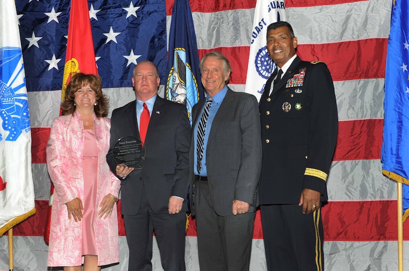 Julie Gerthoffer (left), Charleston Chamber of Military Relations Committee, and U.S. Army Lt. Gen. Vincent Brooks (right), Third Army commanding general, present Tommy Pruitt, communications and marketing director, and Vernon Joynt, chief scientist, from General Dynamics Land Systems-Force Protection, the award for 'Business Support of the Year', during 'Salute to the Military' May 23, 2012 at the North Charleston Convention Center, S.C. This is the eighth year the Charleston Metro Chamber of Commerce recognized the local active-duty, reserve, and civilian personnel for their community service above and beyond their call of duty. (U.S. Air Force photo/Airman 1st Class Ashlee Galloway)
