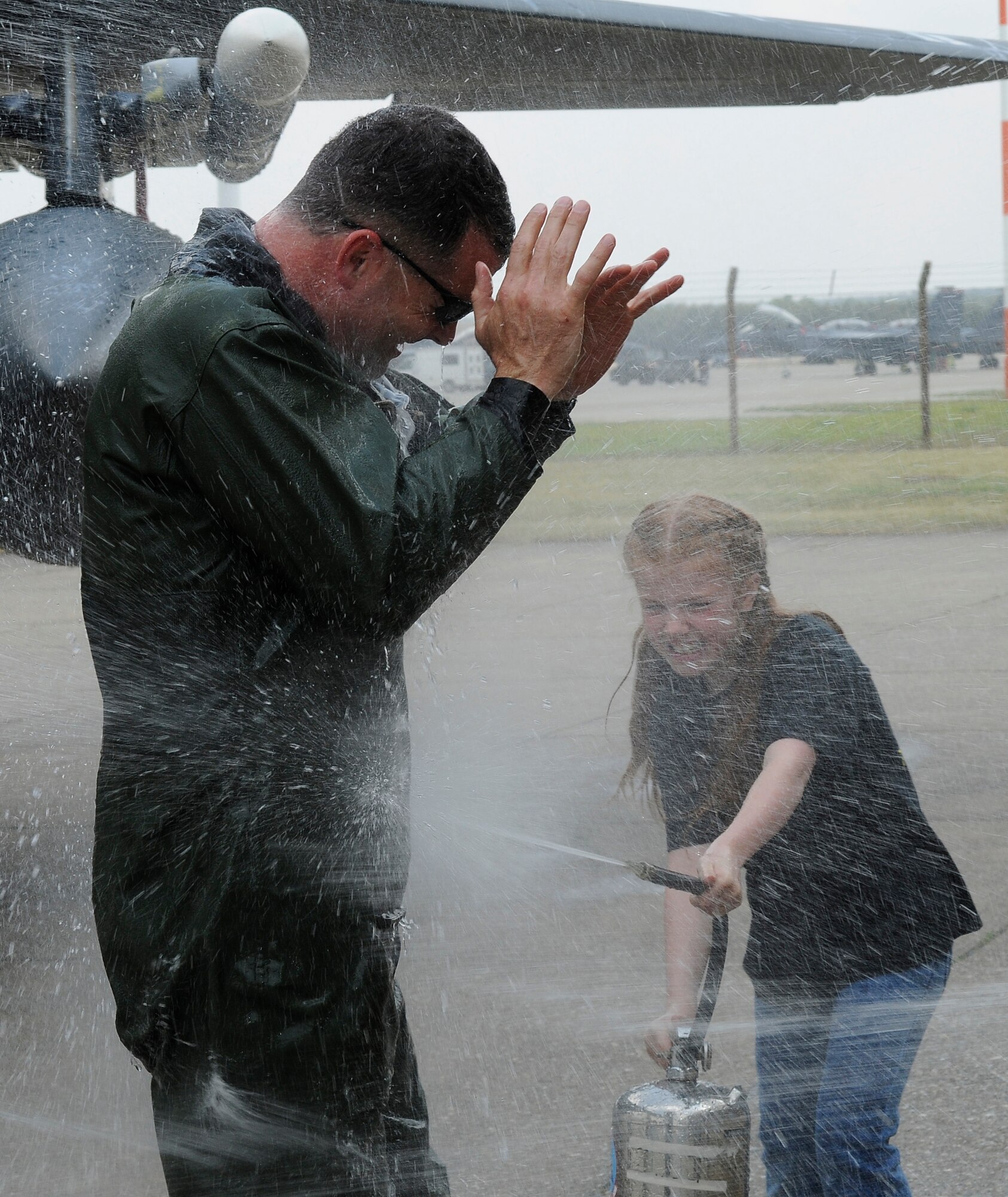 ROYAL AIR FORCE LAKENHEATH, England -- Col. Daniel Orcutt, 48th Operations Group commander, is sprayed with water by his daughter Coby after his "fini" flight May 30, 2012. Orcutt piloted his final flight in an F-15E Strike Eagle after serving two years as the 48th OG commander. (U.S. Air Force photo by Staff Sgt. Connor Estes)