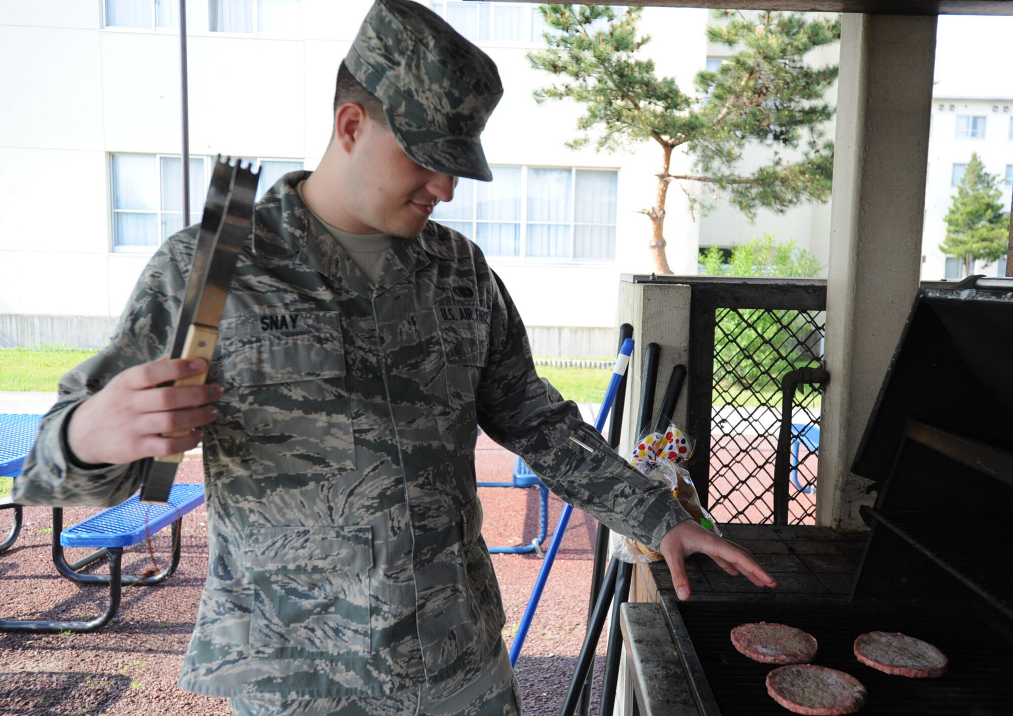 U.S. Air Force Airman 1st Class Kaleb Snay, 35th Fighter Wing public affairs journalist, demonstrates improper grilling techniques by reaching for hot food with his hand instead of using tongs at Misawa Air Base, Japan, June 1, 2012. Using proper grilling equipment and practicing grill safety is the best way to avoid injuries while cooking outdoors. (U.S. Air Force photo by Airman Kenna Jackson/Released)