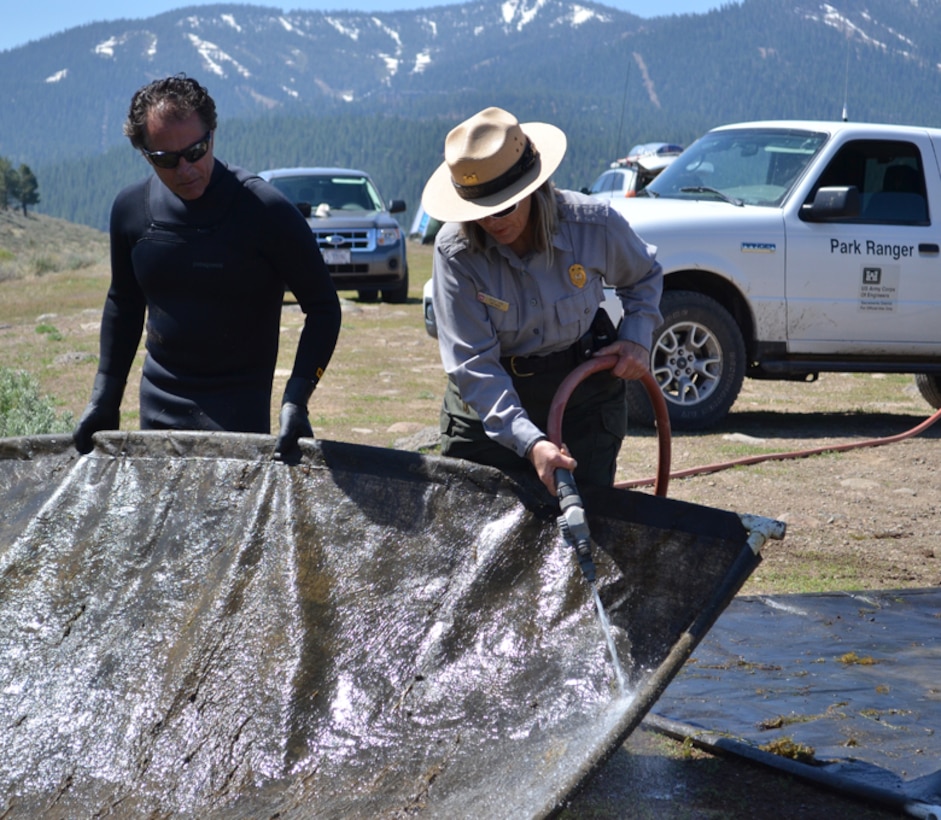 Sacramento District park ranger, Jacqui Zink (right), and Tahoe Divers Conservancy director, Phil Caterino, clean a weed barrier from Martis Creek Lake in Truckee, Calif., during a removal, cleaning and replacement project May 19, 2012. The gas-permeable barriers kill invasive plants by blocking sunlight, but don't disturb other plant and animal species. The U.S. Army Corps of Engineers and Tahoe Divers Conservancy have teamed up to sustainably eradicate invasive milfoil at the lake, managed by the Corps’ Sacramento District.