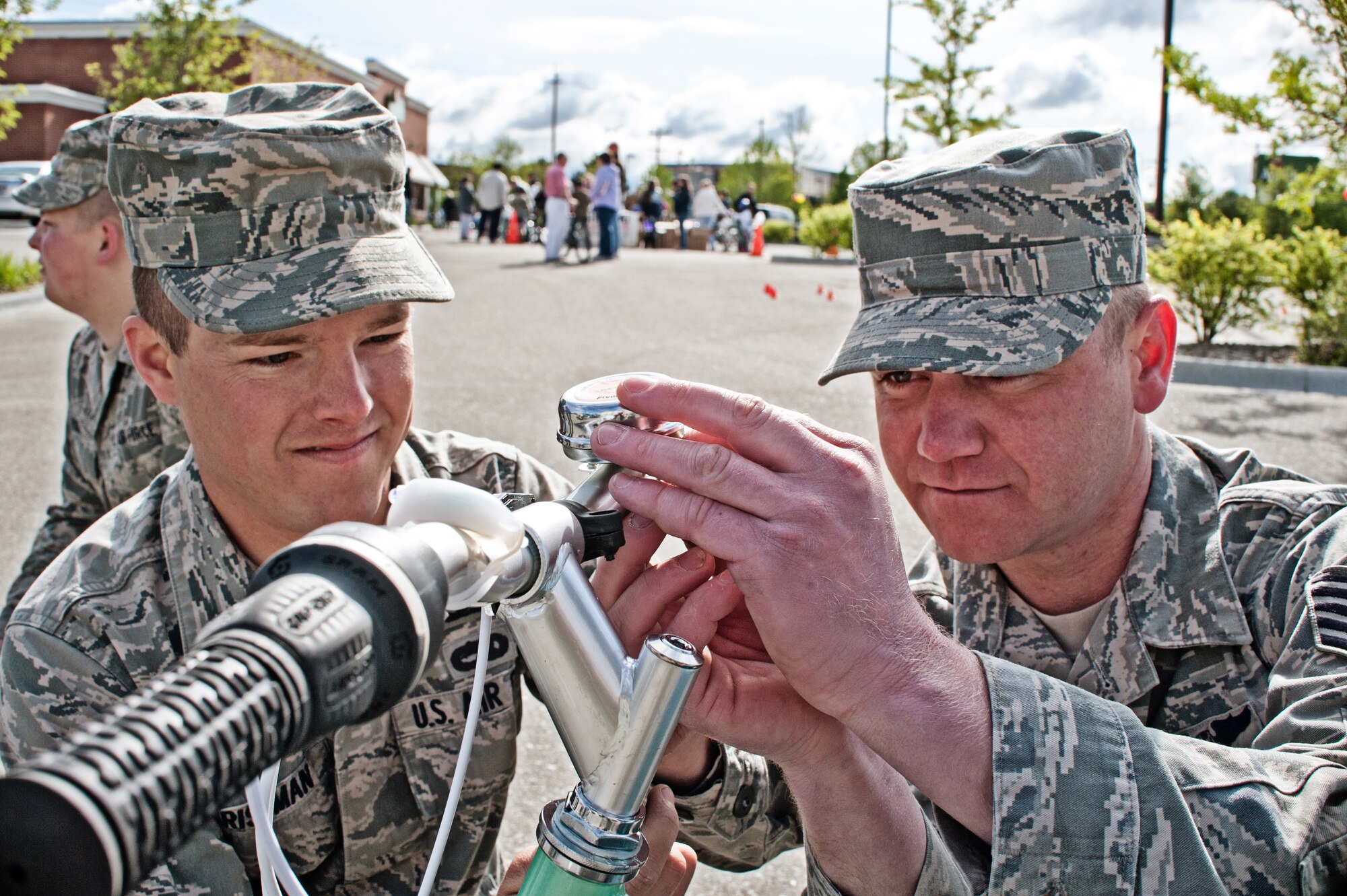 Senior Airman Christopher Christman and Tech. Sgt. Jason Fontaine, vehicle maintainers from the 124th Logistics Readiness Squadron, install a safety bell on a new bike as part of Burgers for Bikes, Bikes for Kids May 5 at Applebee's Restaurant on Vista Avenue in Boise. For 20 years, Idaho Air National Guard volunteers have transported and provided on-site repairs and adjustments to more than 5,250 bikes for deserving youth who are nominated through local schools. (Air Force photo by Tech. Sgt. Becky Vanshur)
