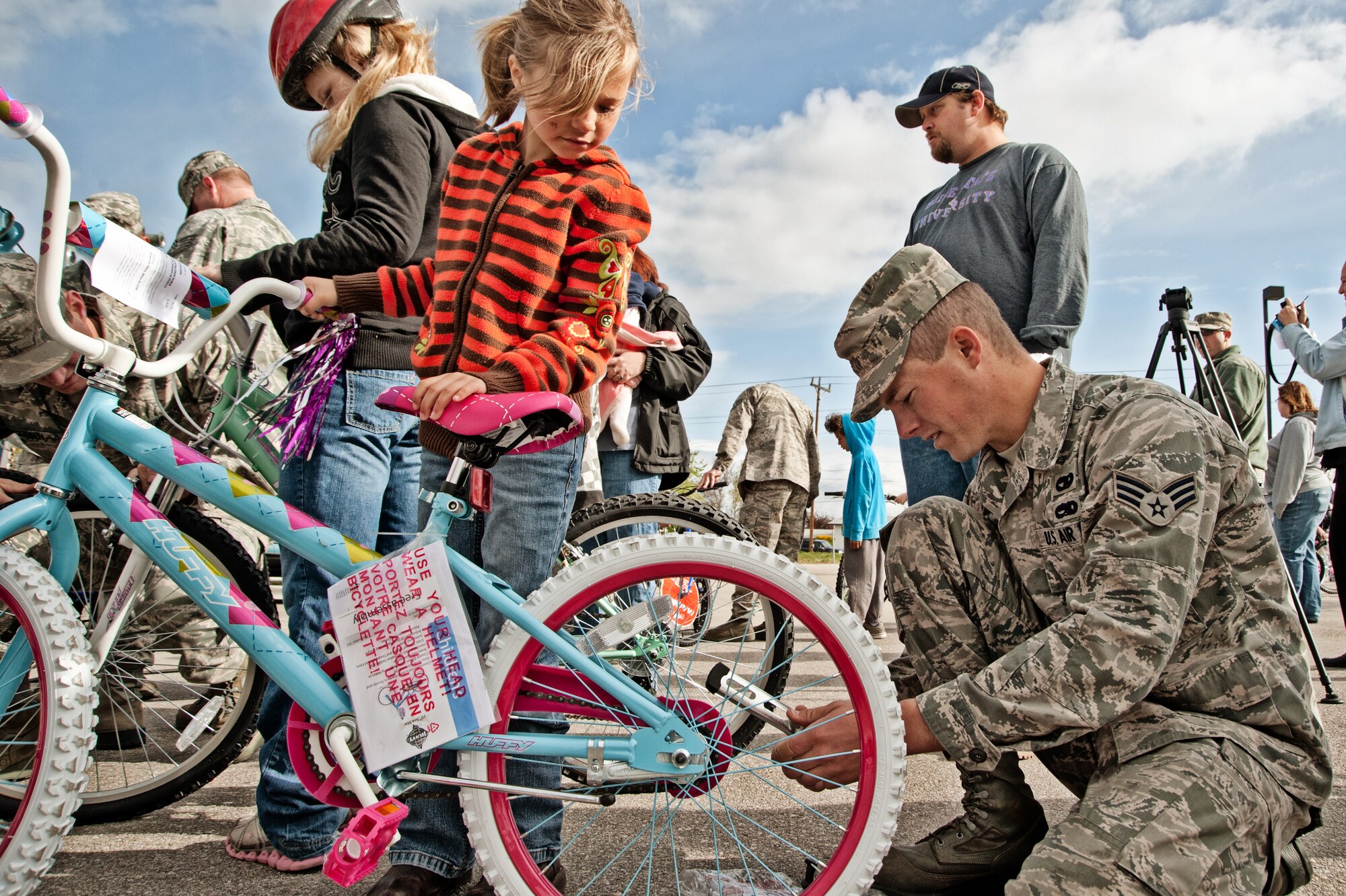 Senior Airman Christopher Christman, 124th Logistics Readiness Squadron, helps a child with her new bike provided by the Burgers for Bikes, Bikes for Kids program, May 5, at Applebee's Restaurant on Vista Avenue in Boise. For 20 years, Idaho Air National Guard volunteers have transported and provided on-site repairs and adjustments to more than 5,250 bikes for deserving youth who are nominated through local schools. (Air Force photo by Tech. Sgt. Becky Vanshur)