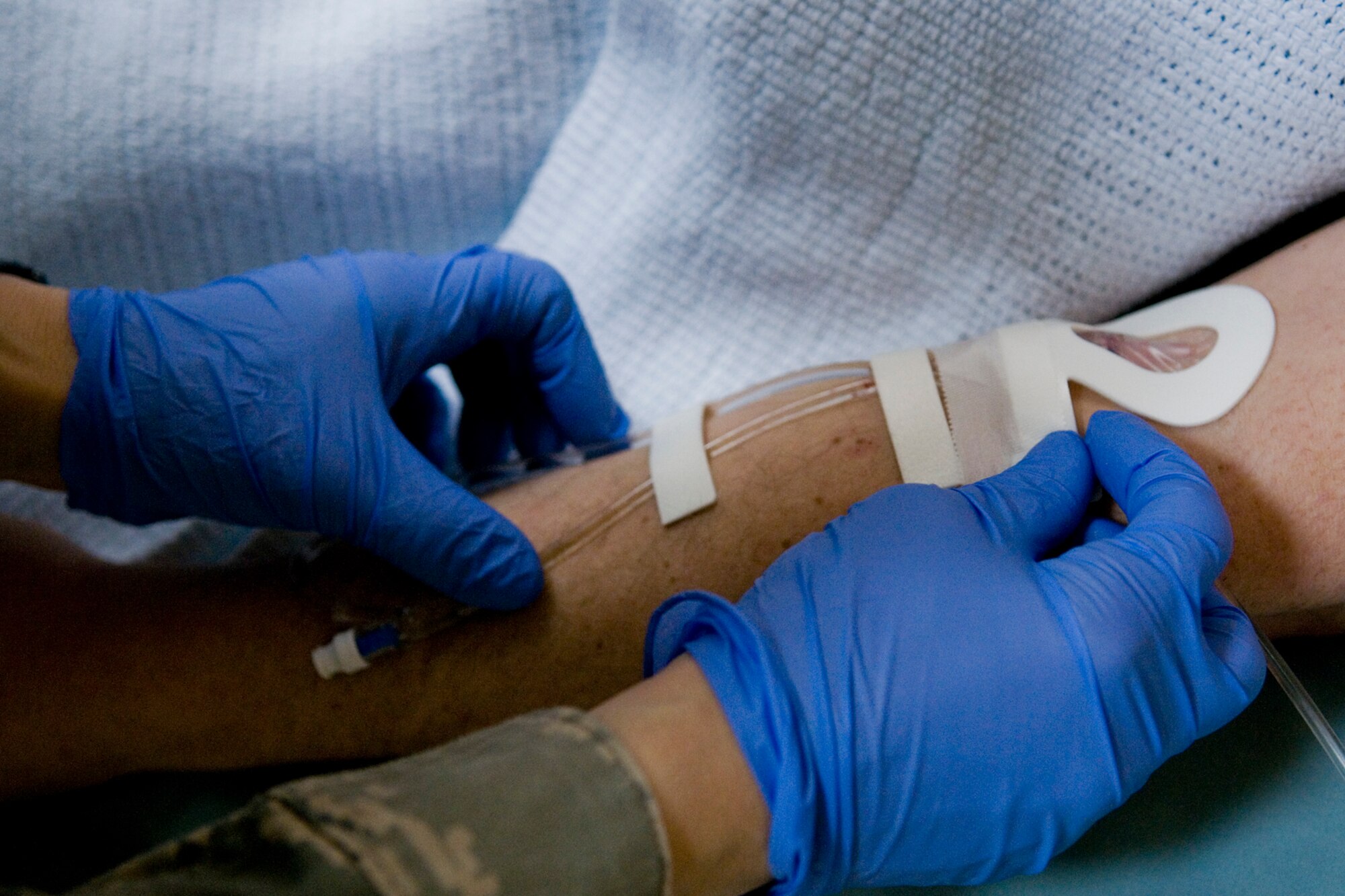 GRISSOM AIR RESERVE BASE, Ind. -- Tech Sgt. Rosalba DeLapaz, 74th Air Refueling Squadron medical element technician, tapes an intravenous tube to Master Sgt. Mike Morris, 434th Communications Squadron client systems technician, during a recent deployment to Incirlik Air Base, Turkey March 1. The deployers' teamwork and can-do attitude delivered world-class care so that troops wouldn't miss a beat. (U.S. Air Force photo/Senior Airman Jami K. Lancette) 