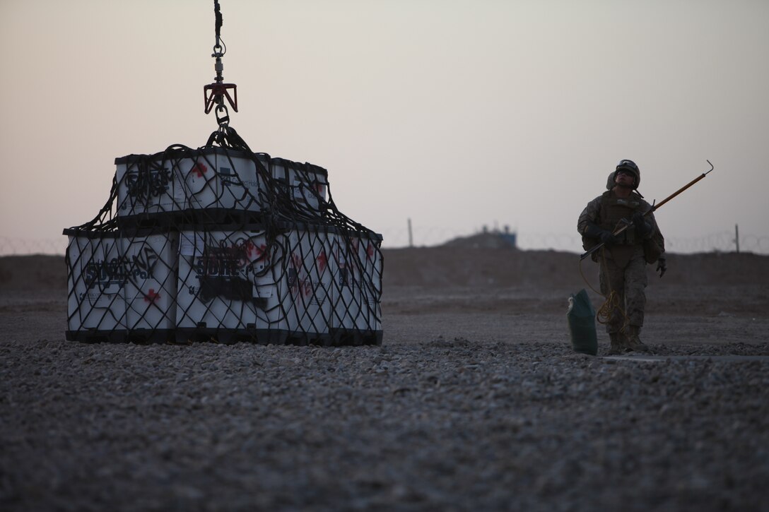 During a Helicopter Support Team operation, a landing support Marine with Combat Logistics Battalion 5, 1st Marine Logistics Group (Forward) walks away from a container after attaching it to the Kaman K1200 unmanned aerial vehicle at Camp Dwyer, Afghanistan, June 3. The HSTs with the UAV are safer than piloted aircraft for Marines working underneath because the longer rope allows the UAV to hover from a higher distance.