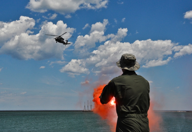 Senior Master Sgt. Shane Loomis, 128th Air Refueling Wing Aircrew Flight Equipment crewmember, Milwaukee, uses a signal flare and pops orange smoke to signal the landing zone location for a UH-60 Black Hawk Helicopter from the Army Aviation Support Facility #1, West Bend, Wis., during the vectoring portion of water survival training on Lake Michigan, Wis., June 2, 2012. 

The water survival and extraction training was a joint exercise with support from the 128 ARW, UH-60 Black Hawk Helicopters, Coast Guard, and Milwaukee Fire Dept.

U.S. Air Force Photo by Staff Sgt. Jeremy M. Wilson
