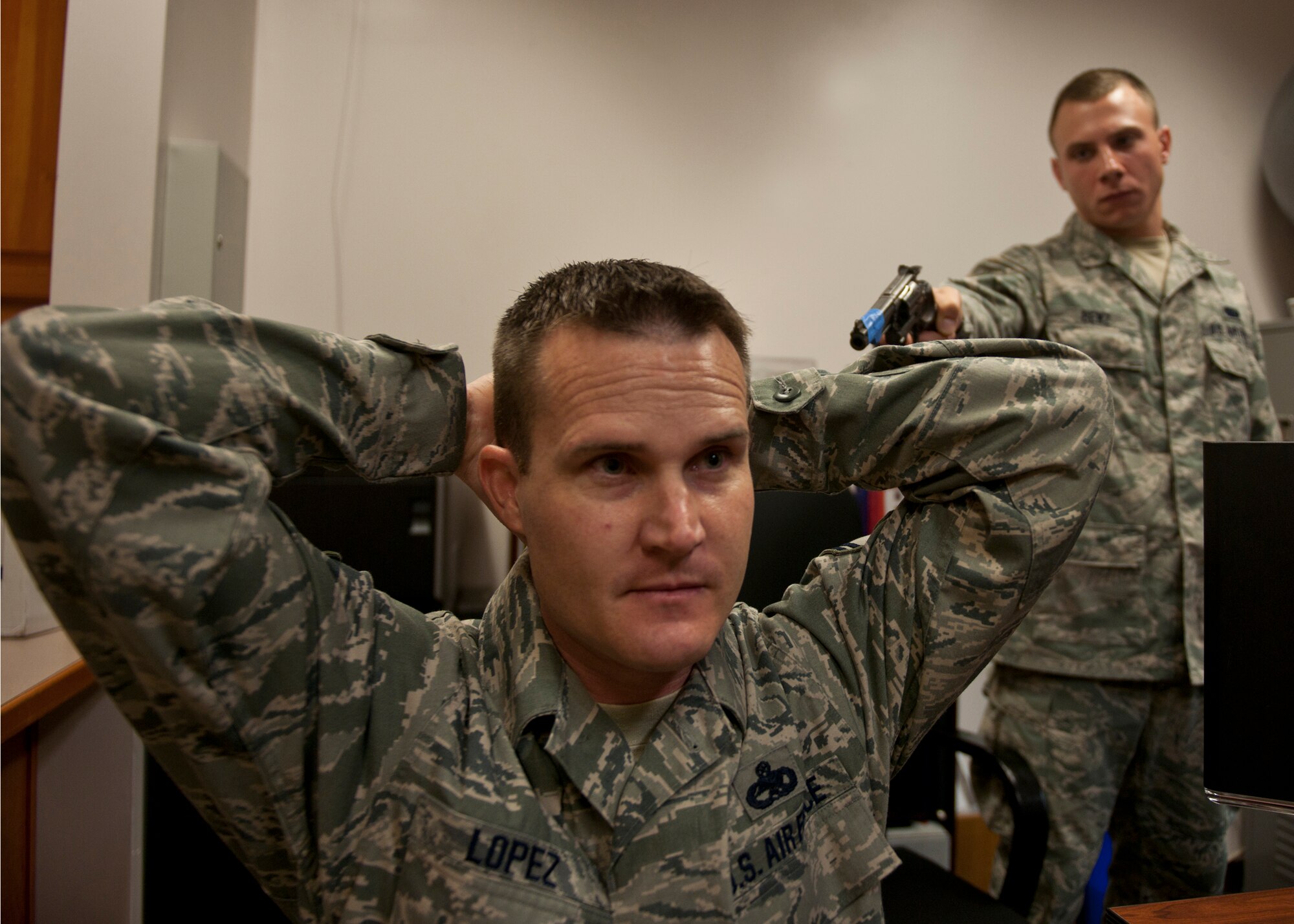 U.S. Air Force Senior Master Sgt. Scott Lopez, 476th Maintenance Squadron, is held at gun-point by Senior Airman Jeffrey Benz, 23d Maintenance Group, during an active shooter exercise June 1, 2012, at Moody Air Force Base, Ga. Benz played the role of an active shooter. The entire base participated in the exercise and underwent an hour-long lockdown to test Moody’s actions and procedures in response to situations involving a gunman. (U.S. Air Force photo by Senior Airman Eileen Meier/Released)