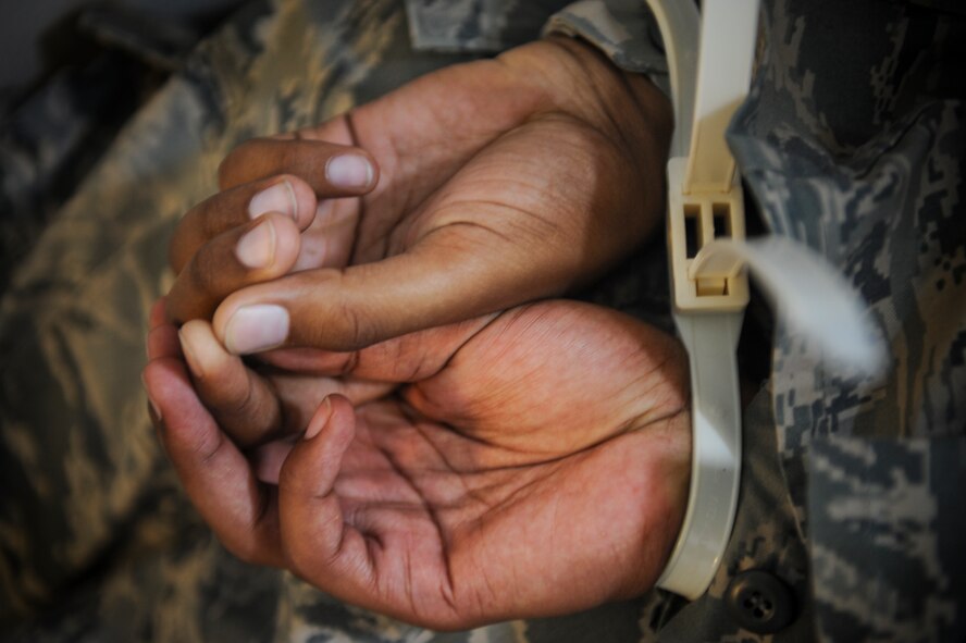 U.S. Air Force Airman 1st Class Michael Kinsey, 23d Medical Operations Squadron plans and scheduling apprentice, lies on the floor after being handcuffed by security forces during an active shooter exercise at Moody Air Force Base, Ga., June 1, 2012. The security forces Airmen successfully cleared the building, evacuated the injured hostages and detained the gunman. (U.S. Air Force photo by Airman 1st Class Douglas Ellis/Released)
