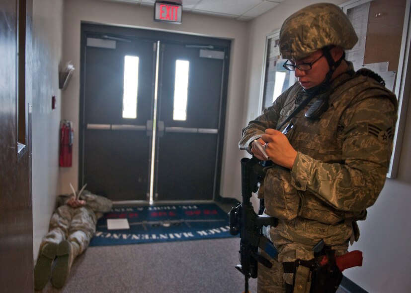 U.S. Air Force Senior Airman Robert Thompson, 23d Security Forces Squadron, annotates the name of an apprehended gunman played by Airman 1st Class Michael Kinsey, 23d Maintenance Operations Squadron, who simulated shooting several people during an active shooter exercise June 1, 2012, at Moody Air Force Base, Ga. Practicing active shooter exercises regularly improves the security and safety of the base in the case of a real incident. (U.S. Air Force photo by Senior Airman Eileen Meier/Released)