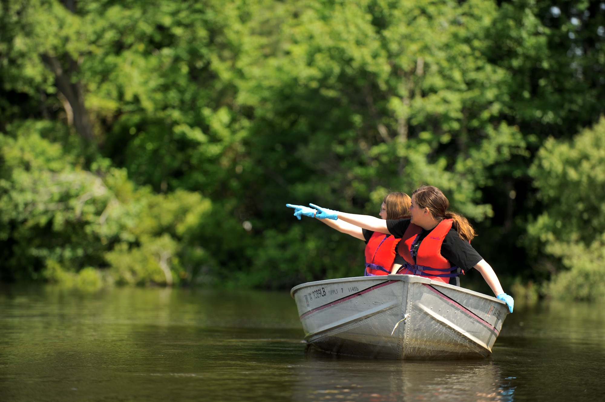 Sitting in the front of a motorboat on the Chesapeake Bay, Va., June 2, 2012, Airman 1st Class Mallorie Poole, 1st Maintenance Squadron line delivery technician, points to a floating piece of trash, as Airman 1st Class Genevieve Wydler, 1st MXS non-destructive inspection technician, points to the same location. Airmen from Langley Air Force Base joined together to collect trash during the 2012 Clean the Bay Day event. (U.S. Air Force photo by Senior Airman Jarad A. Denton/Released)