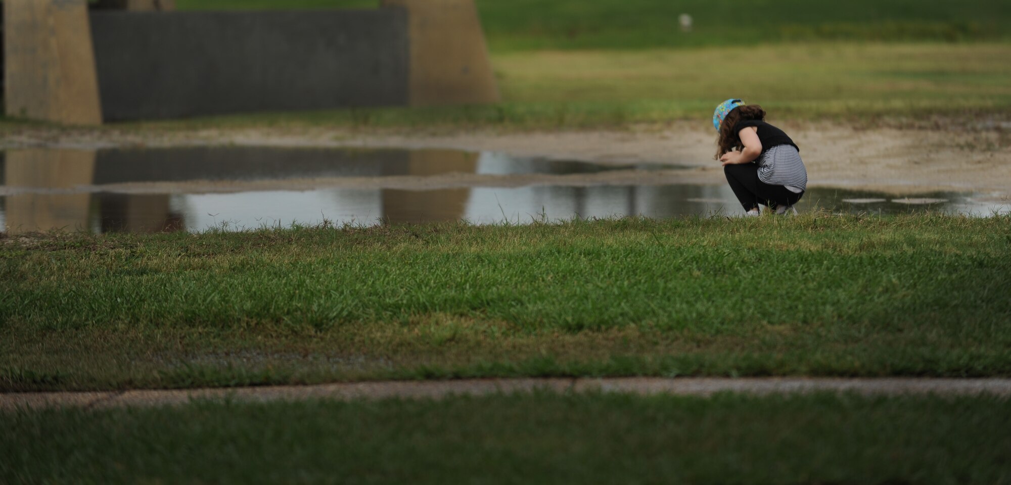 Jillian Gehring, daughter of Master Sgt. Gary Gehring, bends down to remove debris from a puddle of water during the 2012 Clean the Bay Day at Langley Air Force Base, Va., June 2, 2012. Jillian and her father joined volunteers from various organizations on base to pick up trash along the Chesapeake Bay. (U.S. Air Force photo by Senior Airman Jarad A. Denton/Released)