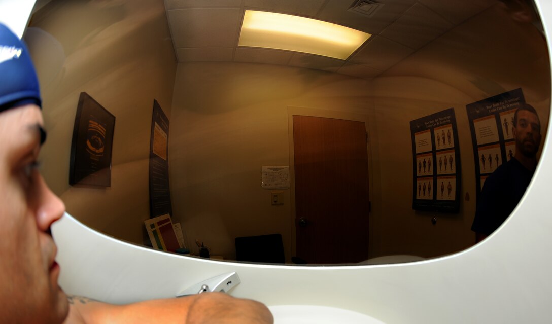 Senior Airman Jarad Denton sits in the BOD POD at the Langley Air Force Base, Va. Health & Wellness Center, as Tony Arroyo, HAWC exercise physiologist, starts the body composition assessment, June 1, 2012. The assessment used air displacement to calculate the body fat percentage, energy expenditure levels and total fat free mass of Denton. (U.S. Air Force photo by Senior Airman Jarad A. Denton/Released)