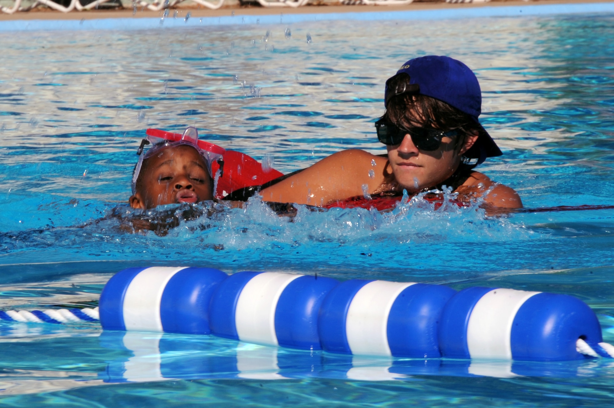 Phillip Wiggins, 6, son of Lt. Col. Janine Wiggins, Air Force Global Strike Command, swims to the other side of the west pool with the assistance of Colton Conrad, Barksdale lifeguard, on Barksdale Air Force Base, La., June 1. Phillip visited the pool with more than 30 other children as a field trip while attending the Barksdale Youth Center summer camp. (U.S. Air Force photo/Senior Airman La'Shanette V. Garrett)(RELEASED)