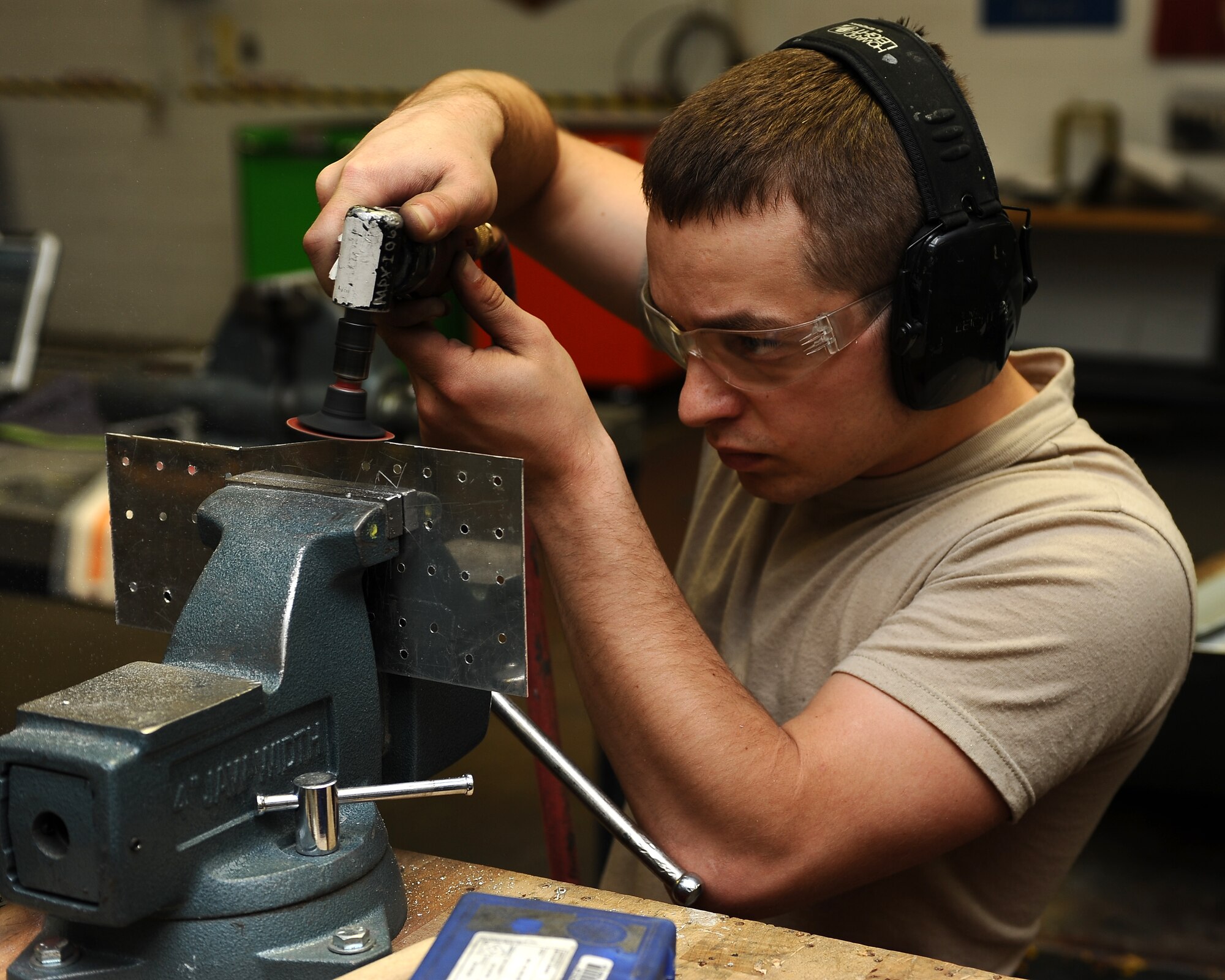 MINOT AIR FORCE BASE, N.D. -- Senior Airman Daniel Richards, 5th Maintenance Squadron aircraft structural maintenance journeyman, uses a pneumatic sander to file a sheet metal patch. The patch of metal being trimmed will be used to repair a crack in the main landing gear door of a B-52H Stratofortress. (U.S. Air Force photo/Airman 1st Class Kristoffer Kaubisch)