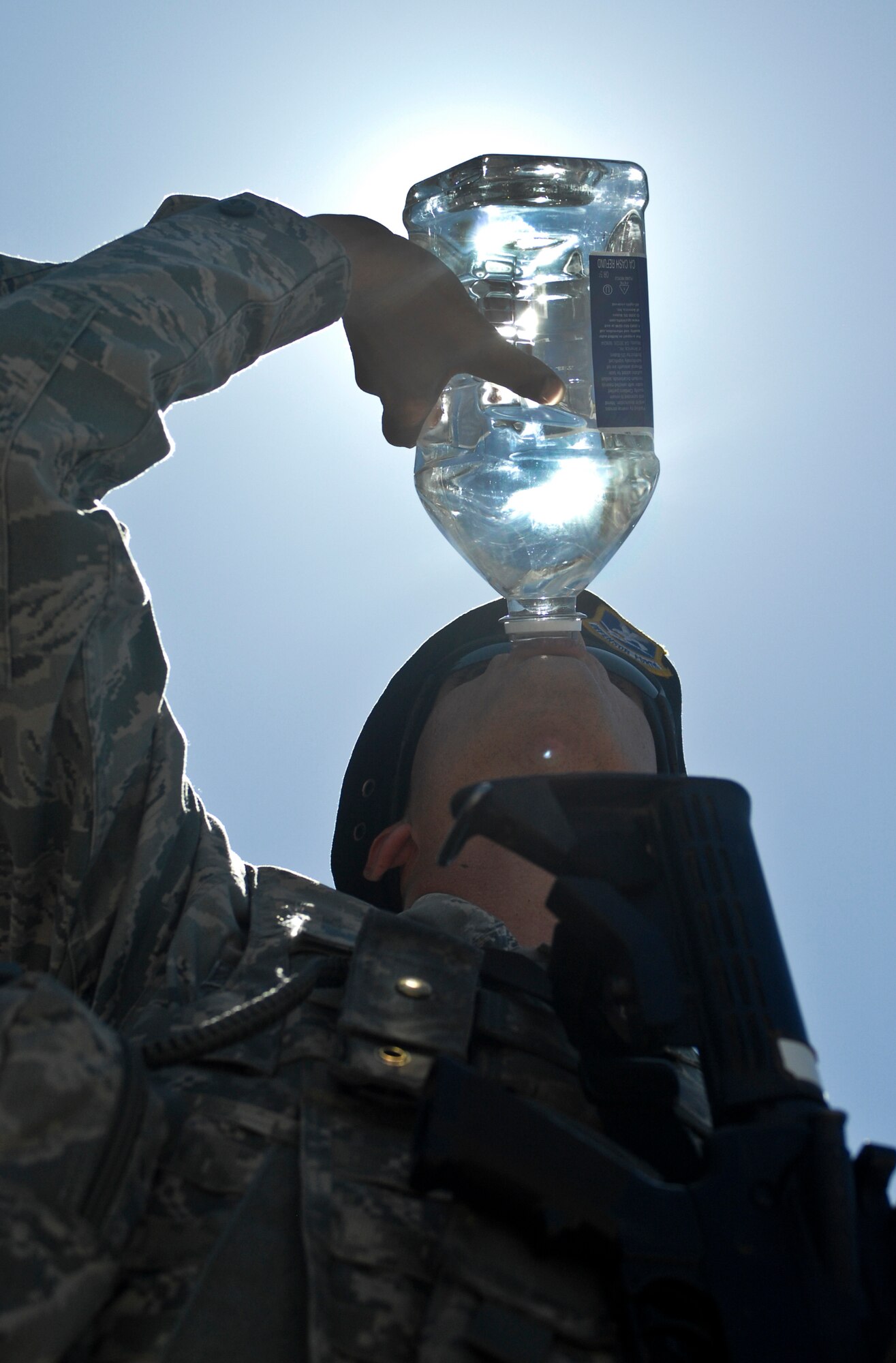 Senior Airman Brendan Raine, 99th Security Forces Squadron patrolman, downs a two liter bottle of water during a patrol June 1, 2012, at Nellis Air Force Base, Nev. With summer temperatures reaching peaks that challenge the body's ability to handle heat, remaining hydrated is as critical to first responders' ability to handle emergencies as any other job preparation step. (Air Force Photo by Senior Airman Jack Sanders)