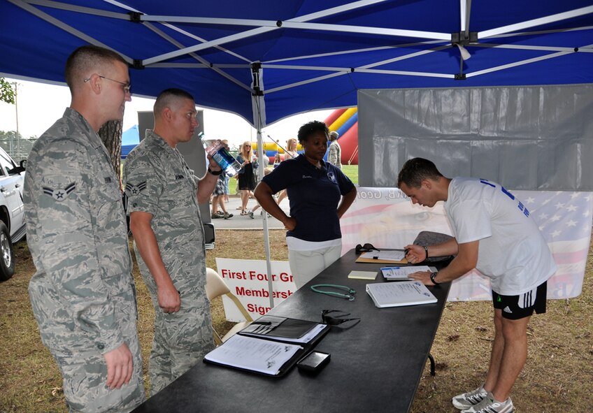 Senior Airman Michael Roman, of the 94th Maintenance Group and president of the Dobbins First Four, and Airman 1st Class Dylan Brown, of the 94th Maintenance Group, sign up potential members for the First Four under the mentorship of the 56 Group. This tent, along with many other tents, housed places for Dobbins Air Reserve Base Airmen to gain information on various subjects from financial planning and education to volunteer opportunities at Family Day on June 3. (U.S. Air Force photo/Senior Airman Elizabeth Gaston)