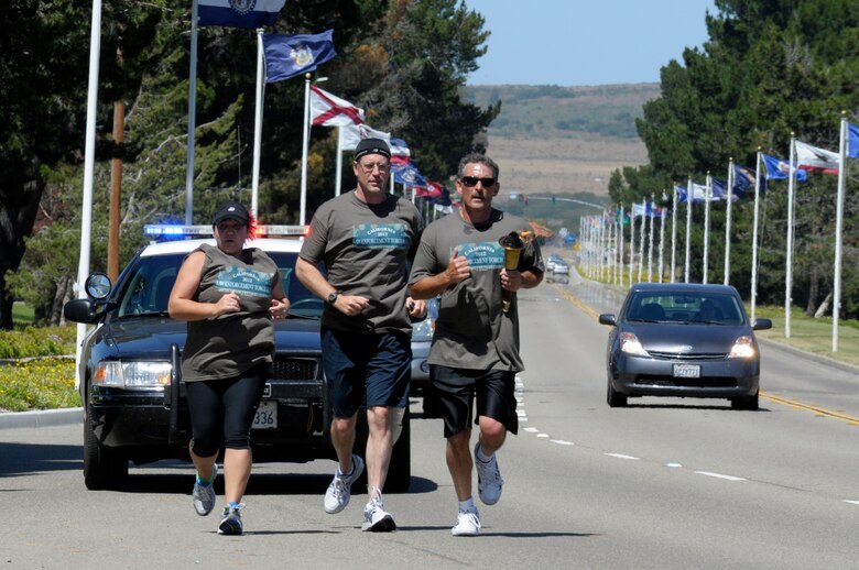 VANDENBERG AIR FORCE BASE, Calif. -- Santa Barbara County Sheriff deputies run the Special Olympics torch down California Boulevard, passing it to 30th Security Forces Squadron members here, Tuesday, June 5, 2012. The Law Enforcement Torch Run passes through Santa Barbara County before its arrival at California State University, Long Beach for the Special Olympics Southern California Summer Games. (U.S. Air Force photo/Jerry E. Clemens Jr.)