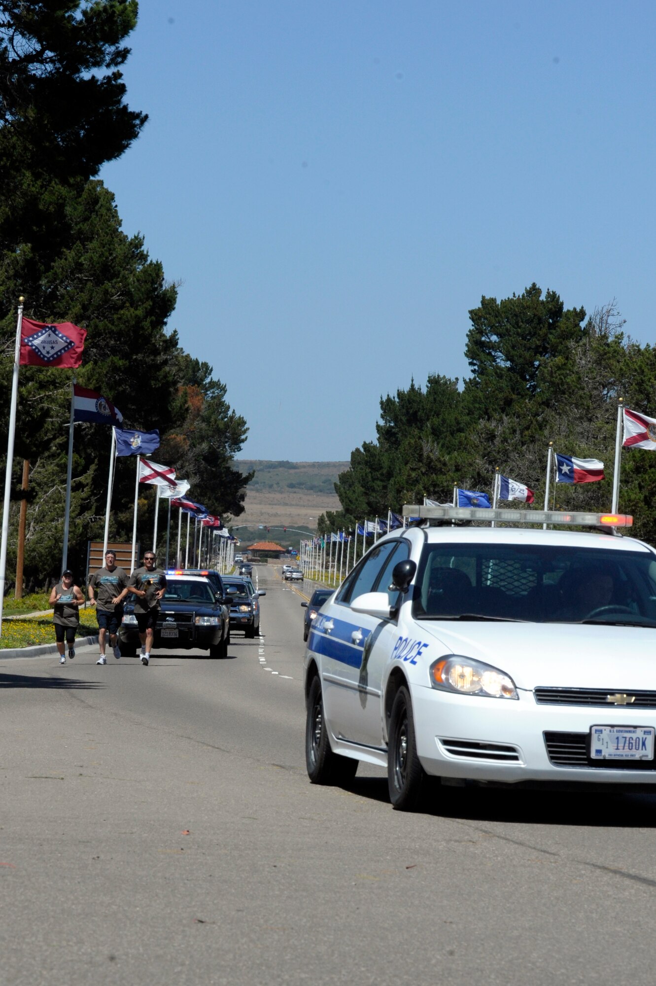 VANDENBERG AIR FORCE BASE, Calif. -- Santa Barbara County Sheriff deputies run the Special Olympics torch down California Boulevard, passing it to 30th Security Forces Squadron members here, Tuesday, June 5, 2012. The Law Enforcement Torch Run passes through Santa Barbara County before its arrival at California State University, Long Beach for the Special Olympics Southern California Summer Games. (U.S. Air Force photo/Jerry E. Clemens Jr.)