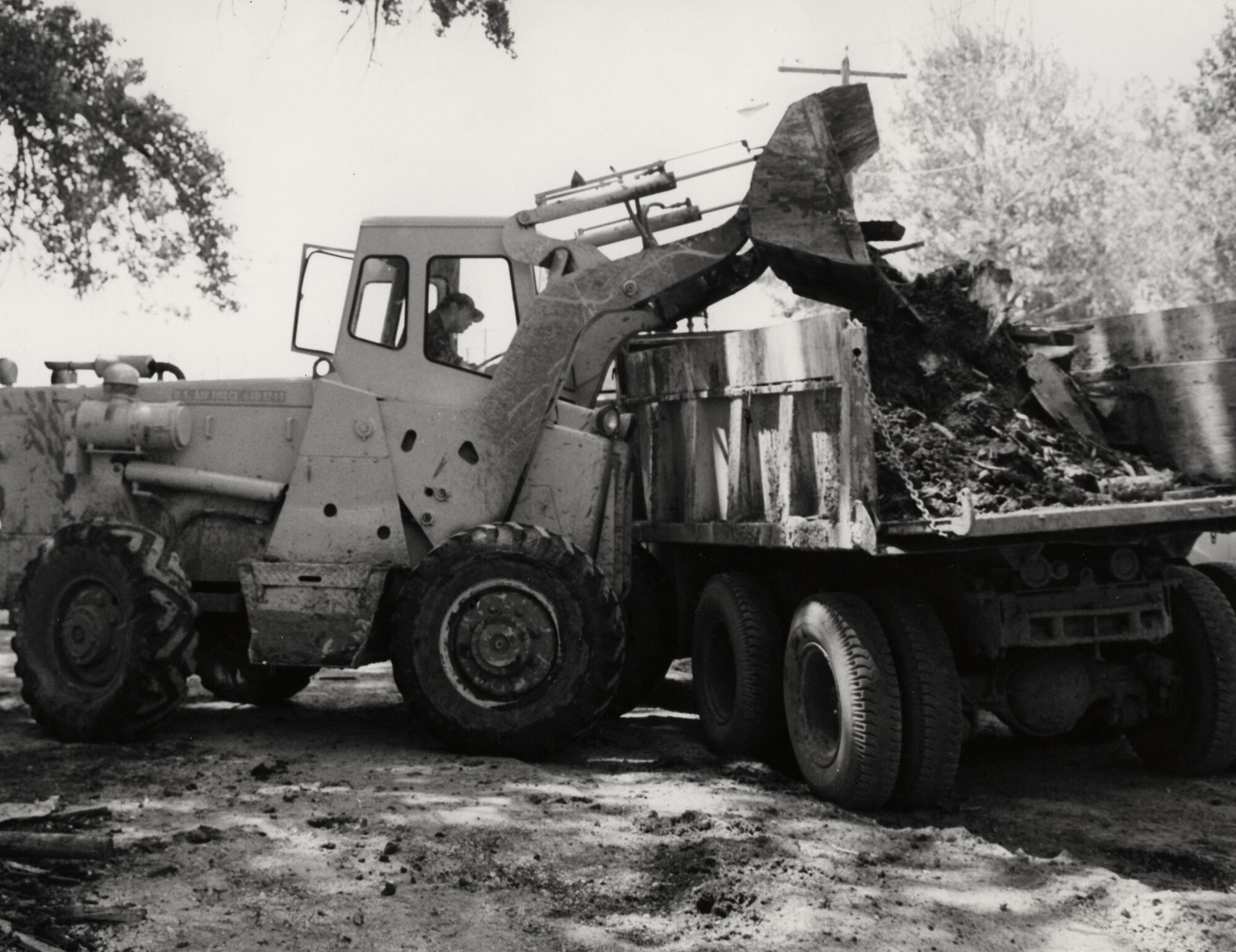 An Ellsworth Airman uses a front end loader to pick up debris around homes and nearby buildings that were damaged after the flood in Rapid City, S.D., June 1972. Nearly 500 Ellsworth Airmen worked with local authorities on June 10, 1972, a number that increased to 1,143 on June 11 and 950 on June 12. Massive amounts of heavy equipment, medical supplies, food and water were dispersed to stricken areas. (U.S. Air Force courtesy photo)