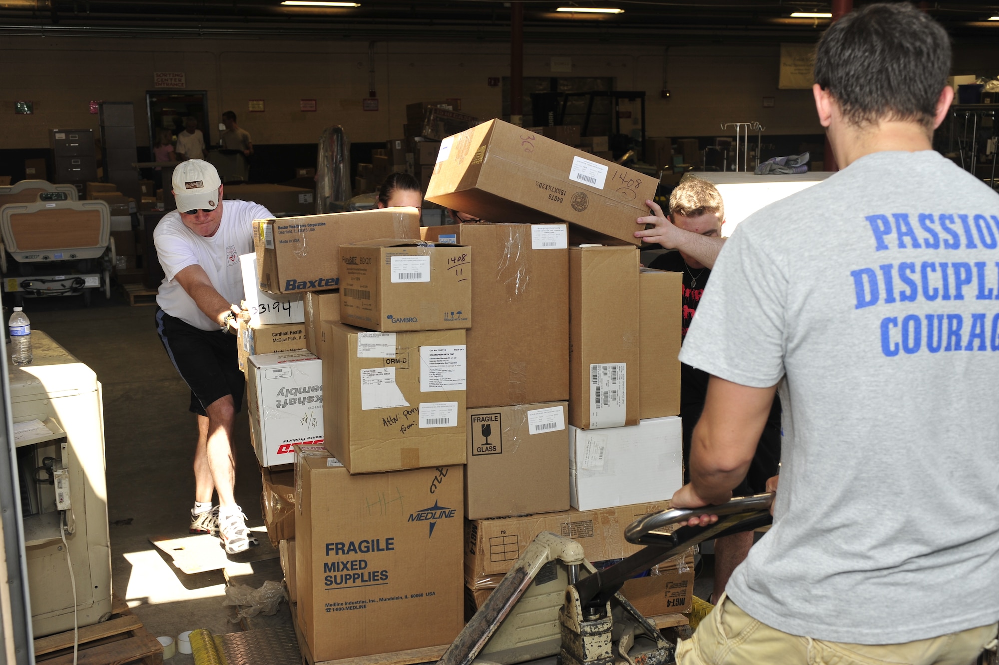 Members of the 56th Security Forces Squadron push a pallet of boxes into a shipping container at the Project Commission on Urgent Relief & Equipment warehouse in Mesa, Ariz., May 31, 2012. The medical supplies, valued at approximately $500,000, were designated for a shipment bound for Guatemala. (U.S. Air Force photo by Staff Sgt. Jason Colbert)