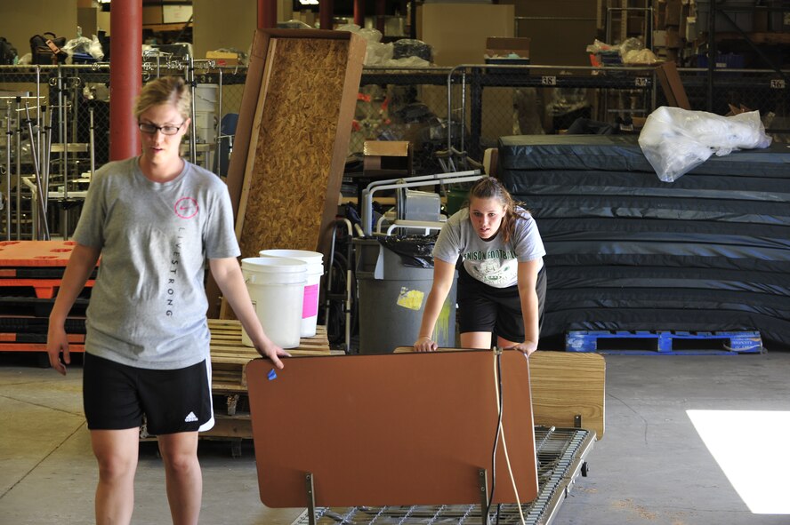 Senior Airman Mariah Langeland, 56th Security Forces Squadron desk sergeant, and Airman 1st Class Ashley Foltz, 56th Security Forces Squadron security patrolman, push a gurney in the Project Commission on Urgent Relief & Equipment warehouse in Mesa, Ariz., May 31, 2012. Members of the 56th SFS volunteered their time to load medical supplies valued at approximately $500,000 for a shipment to Guatemala. (U.S. Air Force photo by Staff Sgt. Jason Colbert)