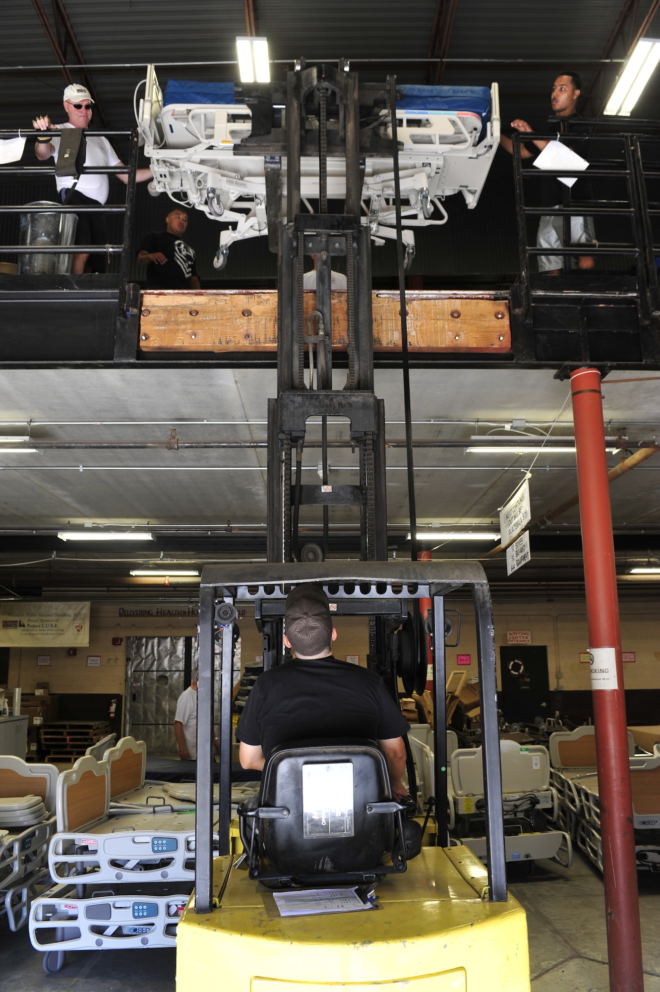 Jerry Haupt (top left), 56th Security Forces Squadron standards and evaluations, and Staff Sgt. Steven Bruner, 56th SFS military working dog handler, place a gurney on a forklift for shipment to Guatemala in the Project Commission on Urgent Relief & Equipment  warehouse in Mesa, Ariz., May 31, 2012. Project C.U.R.E. ships an average of $500,000 of medical equipment every two weeks to developing countries around the world. (U.S. Air Force photo by Staff Sgt. Jason Colbert)