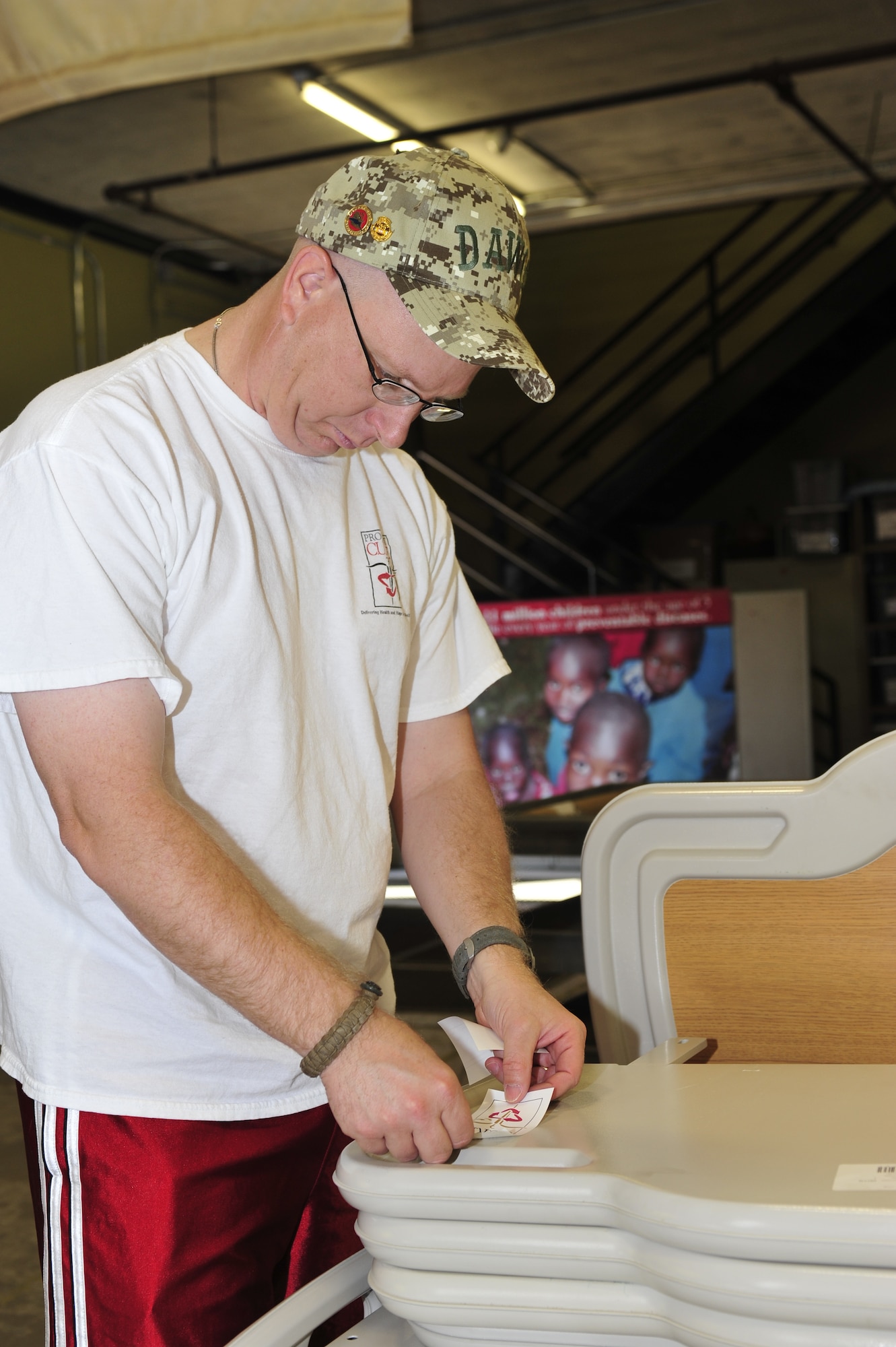 Maj. Jerry Mulhollen, 56th Security Forces Squadron commander, affixes stickers to gurney headboards in preparation for a medical equipment shipment to Guatemala in the Project Commission on Urgent Relief & Equipment  warehouse in Mesa, Ariz., May 31, 2012. Project C.U.R.E. takes donations from countries around America to fill the supply request of developing countries around the world. (U.S. Air Force photo by Staff Sgt. Jason Colbert)