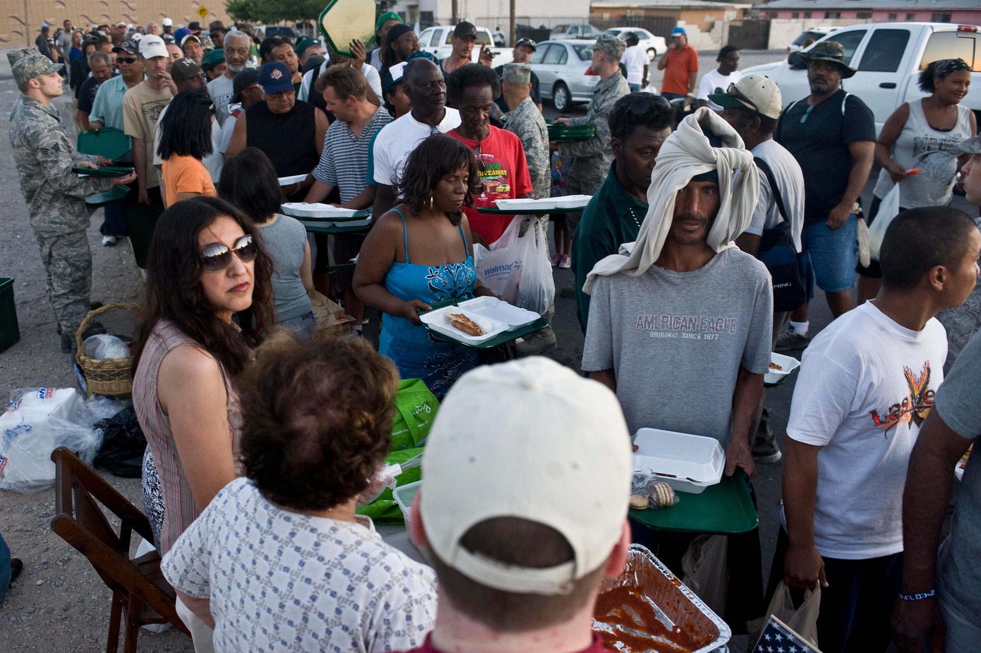 A line of people fill their plates as Airmen from the 57th Maintenance Group, Nellis Air Force Base, Nev., and other local volunteers pass trays out and serve food during a monthly Top-3 Food Drive for the Homeless event May 28, 2012, in Las Vegas. Nellis Airmen serve food one weekend a month to augment the efforts of community volunteer and support organizations. (U.S. Air Force photo by Staff Sgt. Christopher Hubenthal)