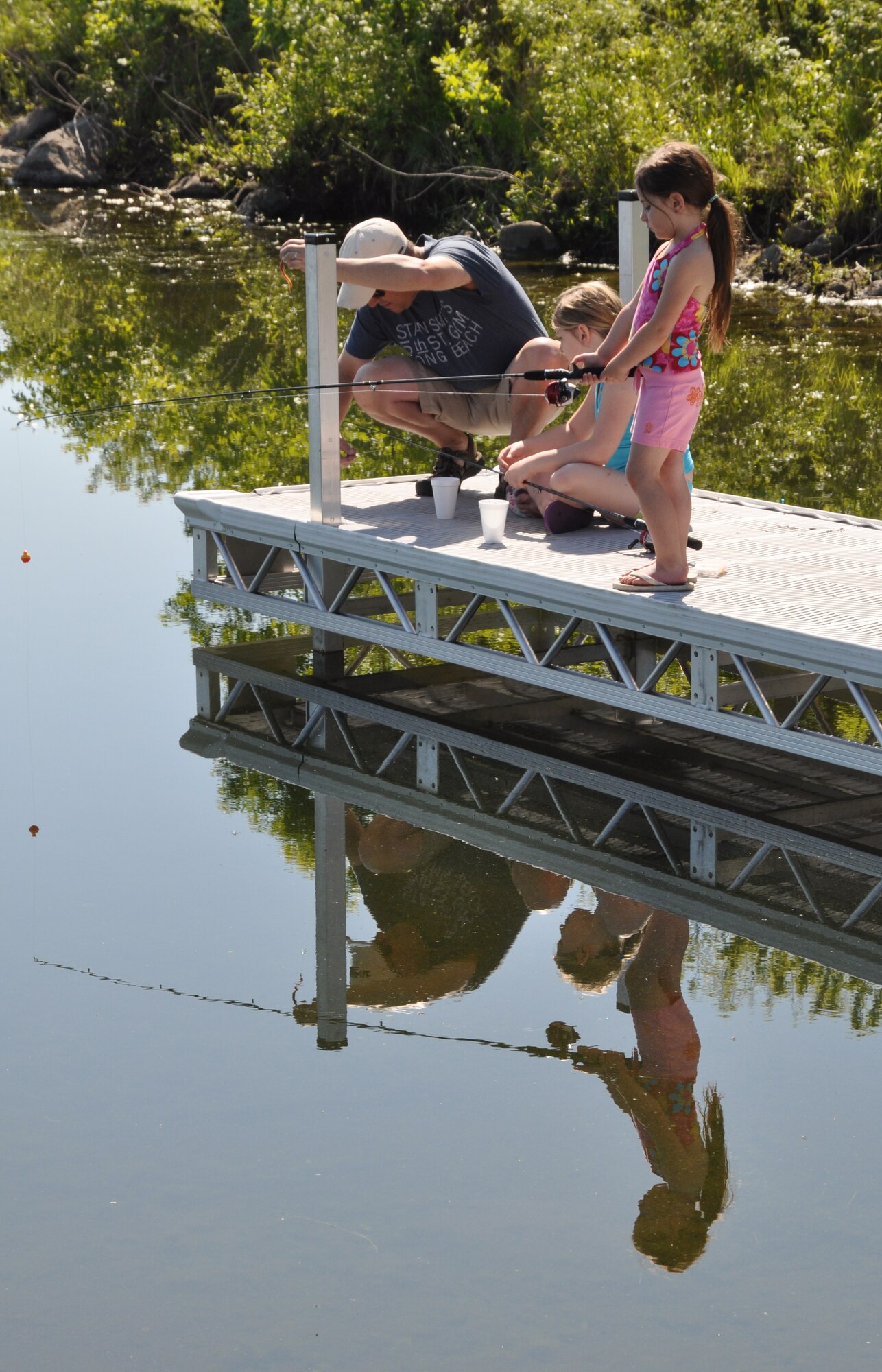 Riley Carriere, 6, fishes while her father, Chris, put bait on the hook for her sister, 9-year-old McKenzie, during the 24th Annual Kid’s Fishing Derby at Larimore Dam, N.D., on June 2, 2012. The 319th Force Support Squadron at nearby Grand Forks Air Force Base hosts the tournament each year. (U.S. Air Force photo/Tim Flack)