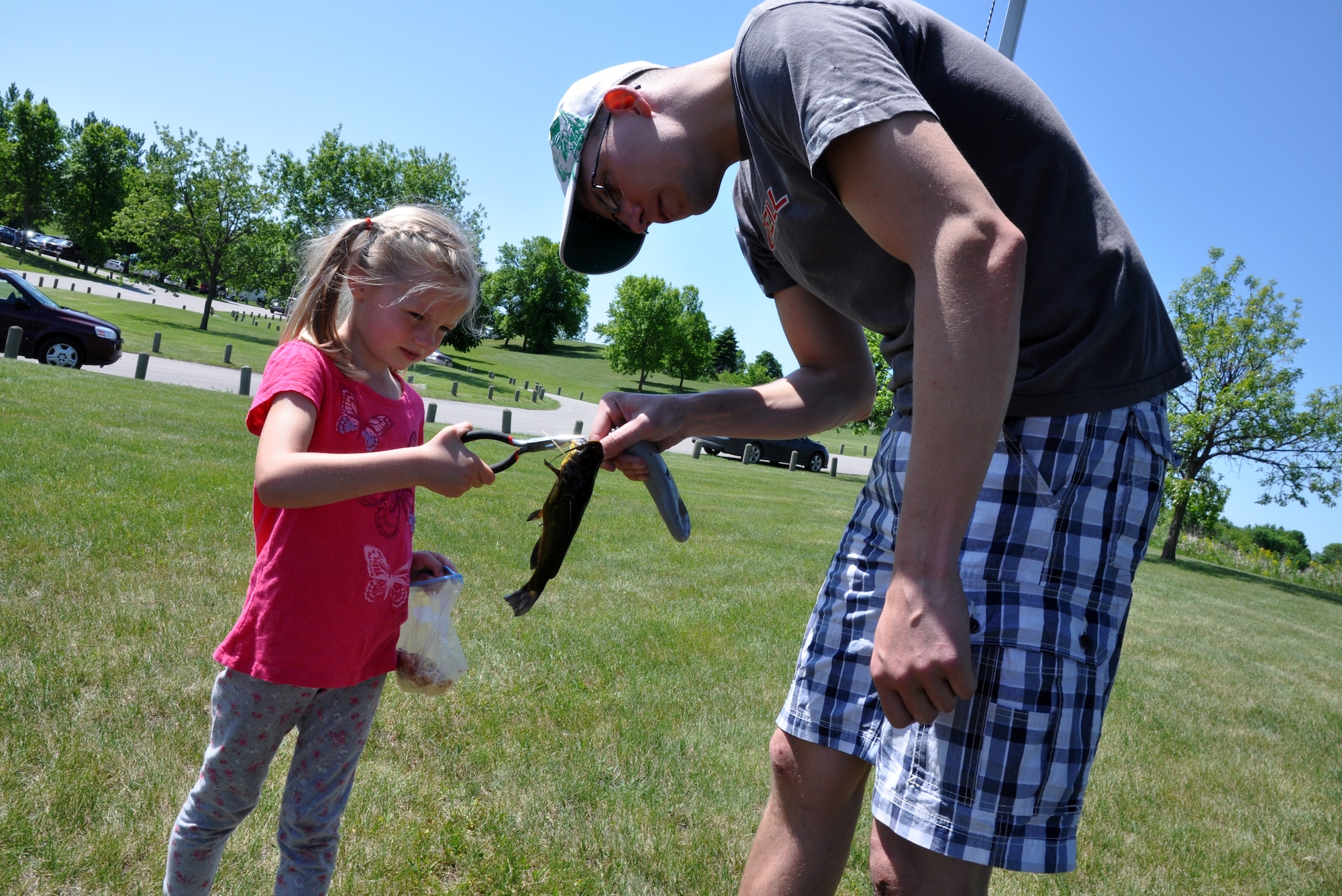 Coral Moberg, 5, gives Staff Sgt. Matthew Nauta a fish to weigh during the 24th Annual Kid’s Fishing Derby at Larimore Dam, N.D., on June 2, 2012. Coral’s little brother, 4-year-old Blaise, caught the fish, according their father, Capt. Matt Moberg, with the 319th Air Base Wing at Grand Forks Air Force Base. (U.S. Air Force photo/Tim Flack)