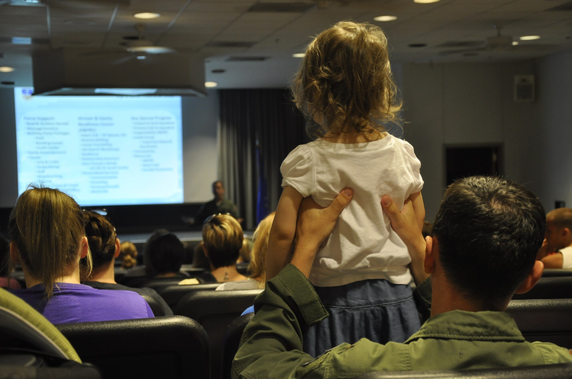 Maj. Matthew Richter, chief of 1st Special Operations Wing safety, holds up his daughter Stella, 3, while listening to a briefing from Col. Jim Slife, commander of 1st SOW, during Commando Spouse Day at the 4th Special Operations Squadron at Hurlburt Field, Fla., May 19, 2012. Hundreds of 1st SOW spouses gathered at the squadron to hear mission briefings and fly on aircraft as part of the day's activities.(U.S. Air Force photo / Senior Airman Joe McFadden) (Released)