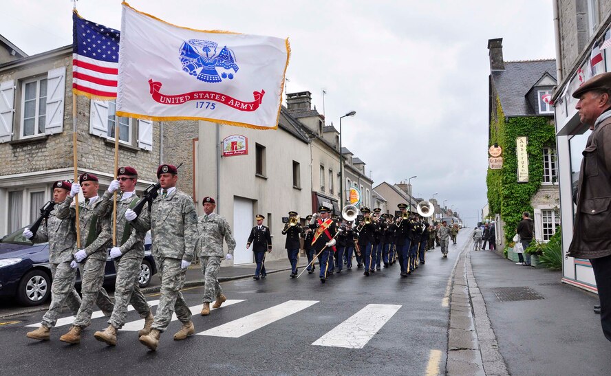 A Frenchman looks on as a U.S. Army color guard leads American and allied troops June 5, 2012, through the streets of Saint Mere Eglise, France, prior to an official ceremony commemorating the 68th Anniversary of the Normandy D-Day invasion. Leadership from the U.S. Army and U.S. Air Force, German military and local French elected officials joined with World War II veterans to lay ceremonial wreaths at the foot of an invasion memorial in the village. Saint Mere Eglise is one of the first villages in the Normandy region to be liberated by Allied forces in the early morning hours of June 6, 1944. (U.S. Air Force photo/Staff Sgt. Stephen J. Collier)