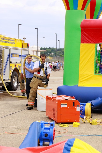 As a safety requirement, Lieutenant Matt Eicher, firefighter with the Airport Authority Fire Department, fills a 50 gallon water drum attached to a bounce house at the 911th Airlift Wing Family Day, June 3, 2012. Safety becomes a main focus at Family Day with such attractions like the bounce house and the rock wall where potential hazards can occur for children. (U.S. Air Force photo by Airman 1st Class Justyne Obeldobel/Released)