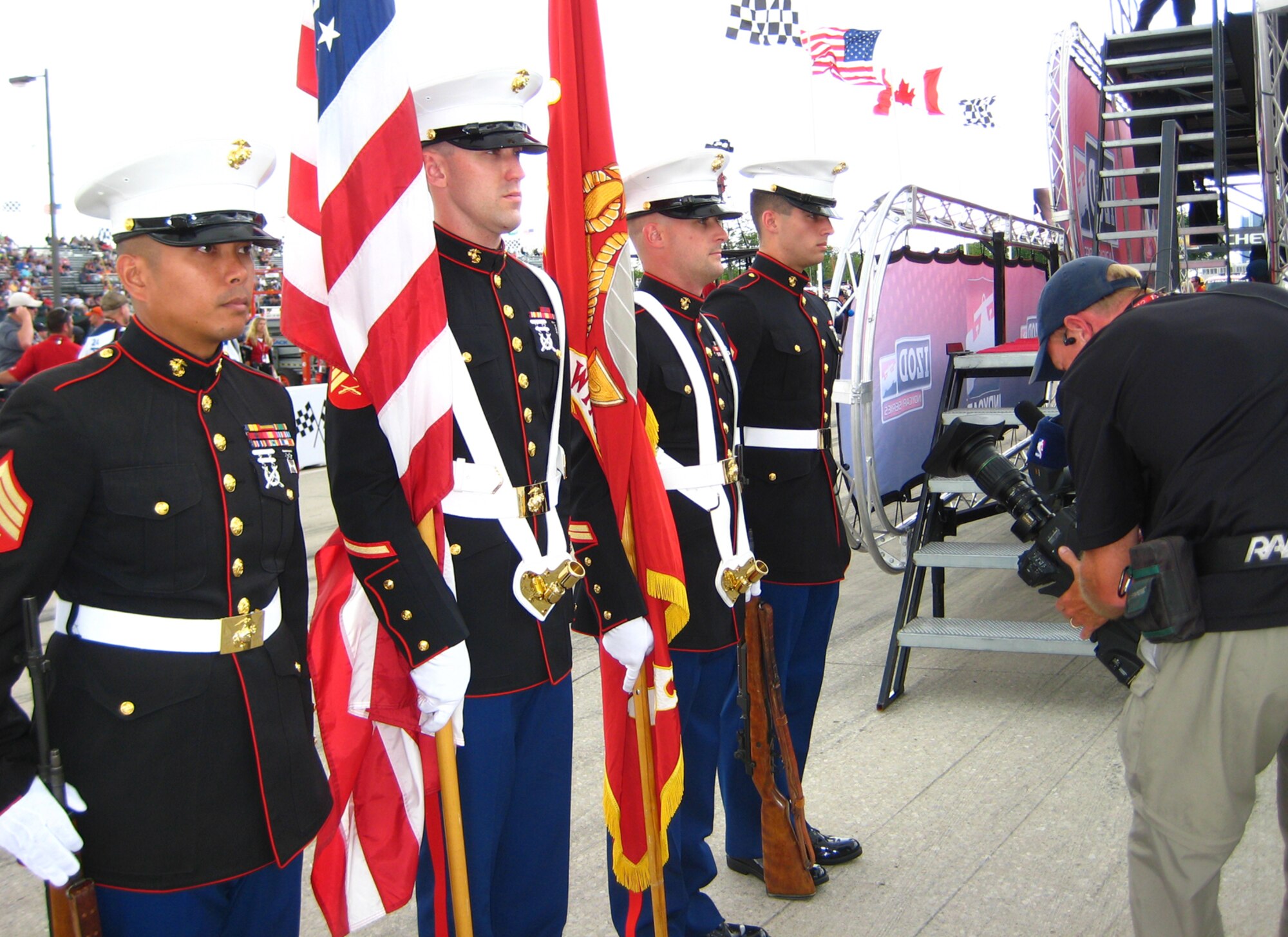 A cameraman films Marines from the 1st Battalion, 24th Marine Regiment Honor Guard prior to the start of the Chevrolet Indy Grand Prix race at Belle Isle in Detroit June 3. The Marines presented the colors during the singing of the National Anthem by legendary Motown group The Four Tops. Grand Prix officials invited 30 military members from Team Selfridge to participate in pre-race activities throughout the race weekend as a way to show their military appreciation. (U.S. Air Force photo by Angela Pope)