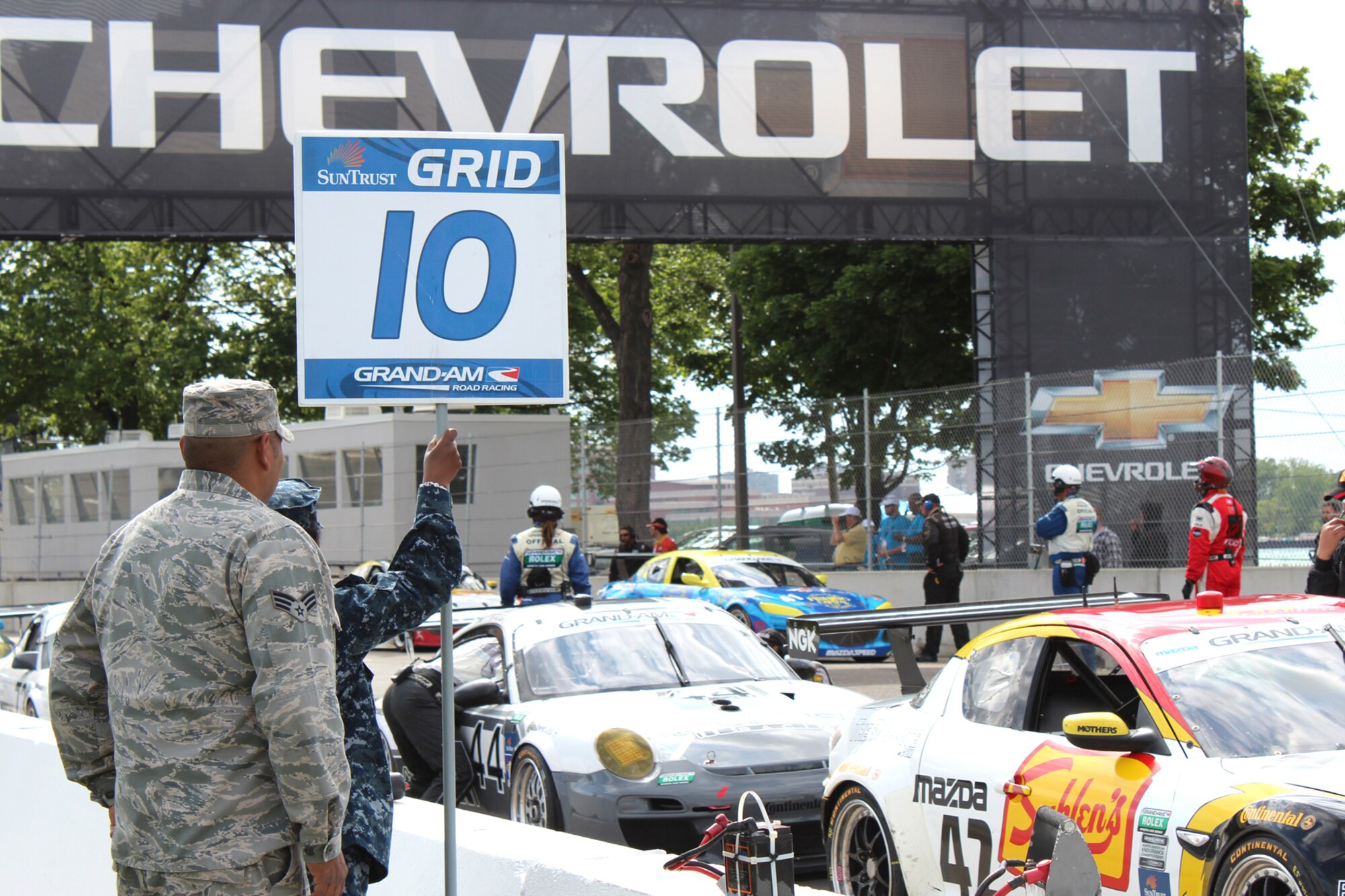 An Airman from the 127th Wing and a Sailor from the Selfridge Navy Operations Support Center serve as grid marshals for the Chevrolet GRAND-AM 200 at the Belle Isle Grand Prix in Detroit June 2. Grand Prix officials invited 30 military members from Team Selfridge to participate in pre-race activities throughout the race weekend as a way to show their military appreciation. (U.S. Air Force photo by Angela Pope)
