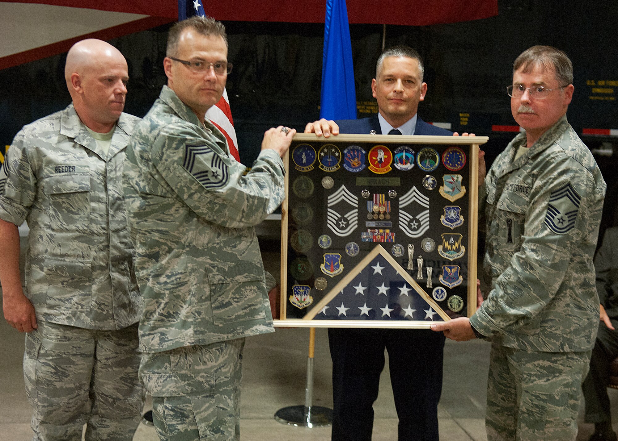 Chief Master Sgts. Monty Reeder, Stacey Weber, both with the 90th Maintenance Group, and Michael Whittaker, 90th Missile Maintenance Squadron, present Chief Master Sgt. Stephen Hrkach, 90th Maintenance Operations Squadron, with a shadow box during his retirement ceremony May 18 in the 90th MXG headquarters building. (U.S. Air Force photo by R.J. Oriez)