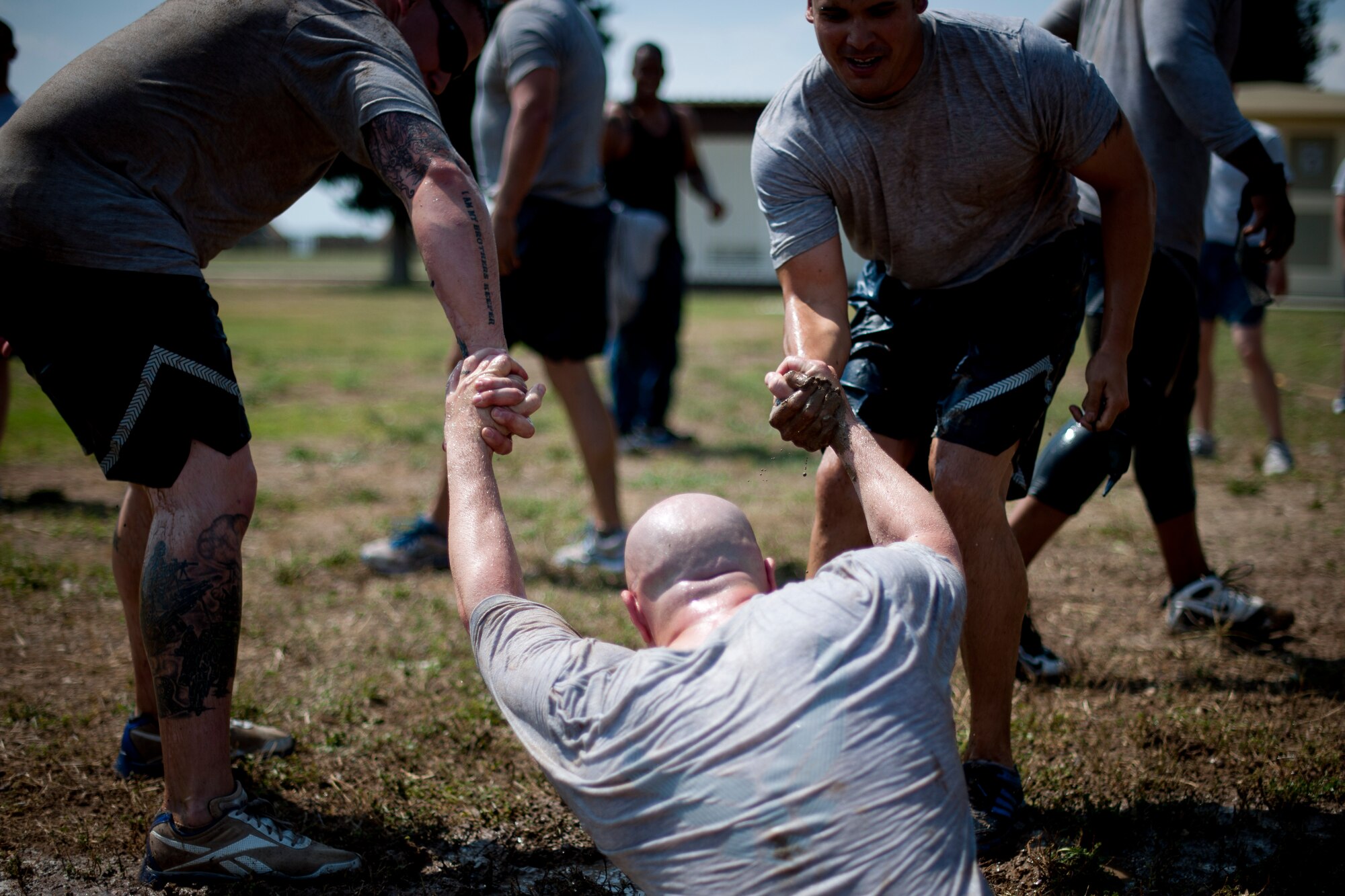 Members of the 39th Security Forces Squadron help a teammate out of a mud pit after a tug-of-war match during the 39th Air Base Wing Sports Day June 1, 2012, at Incirlik Air Base, Turkey. The 39th SFS team took first place overall for tug-of-war. (U.S. Air Force photo by Tech. Sgt. Michael B. Keller/Released)
